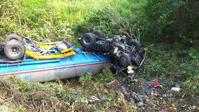 油罐車遭撞後翻落三樓高邊坡。(消防局提供)