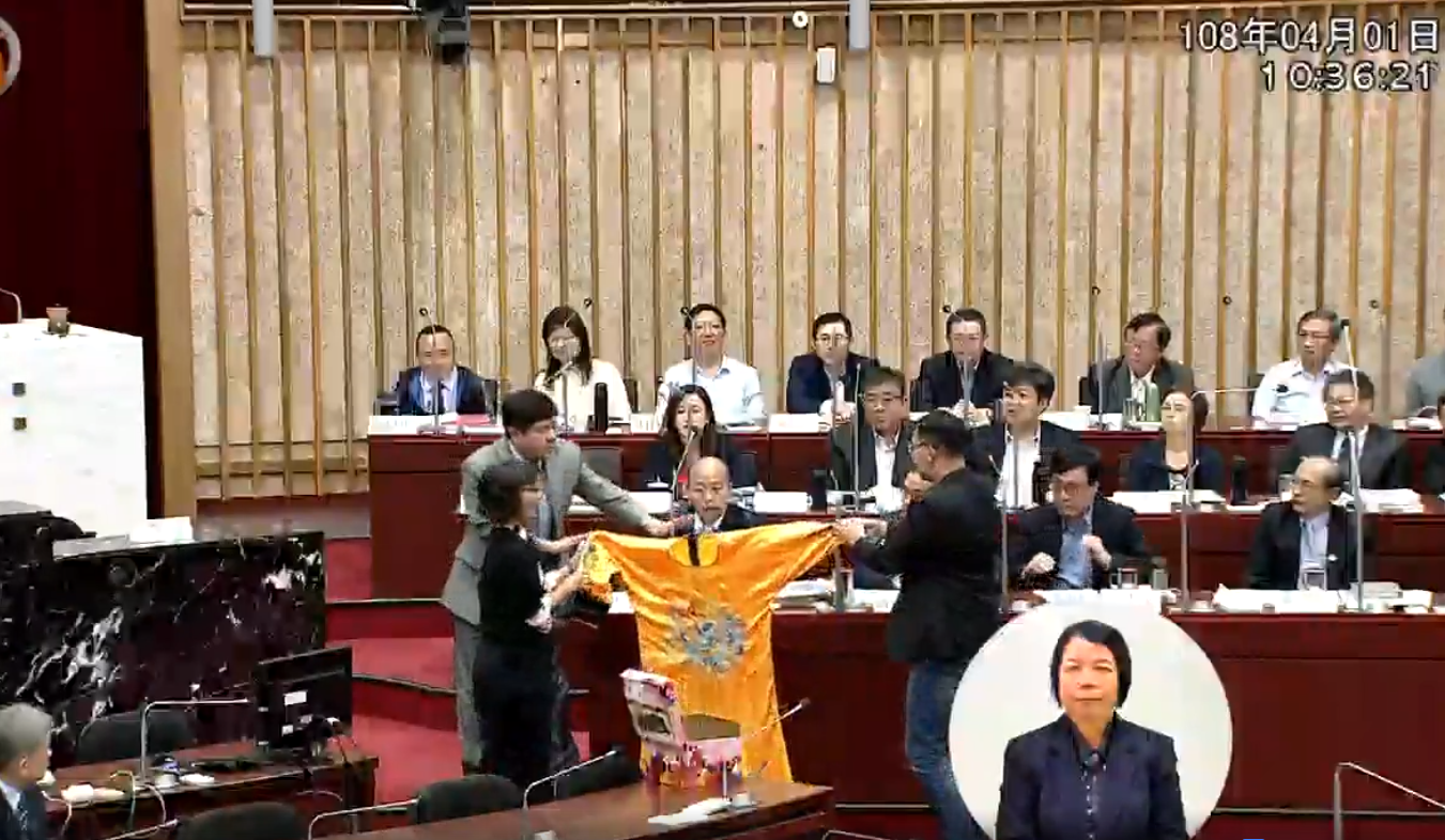 民進黨團送上黃袍給韓國瑜，希望韓國瑜能勇敢地給出要不要參選2020總統的決定。（翻攝高雄市議會）