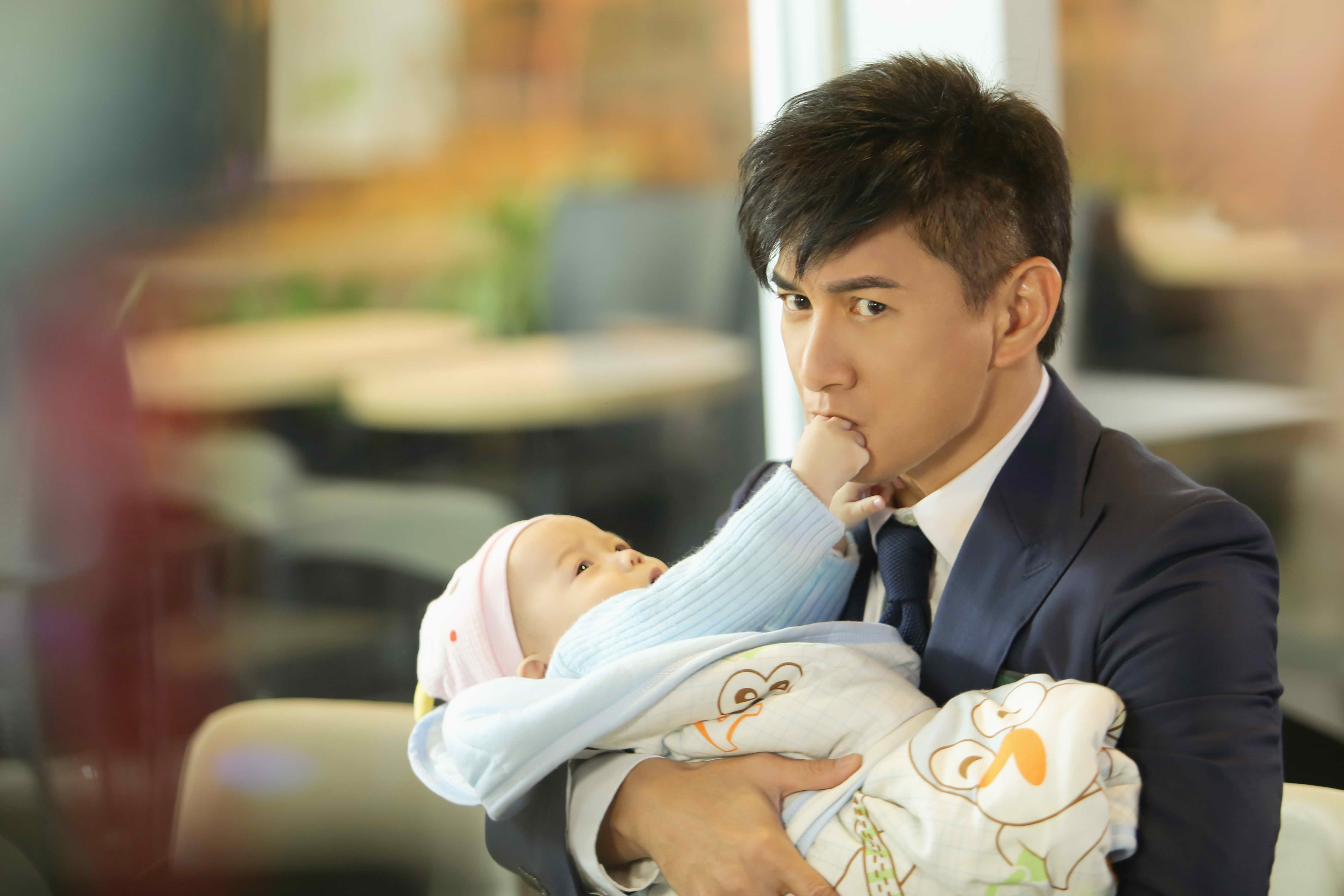 吳奇隆穿著西裝抱著嬰兒,畫面逗趣。(八大提供)