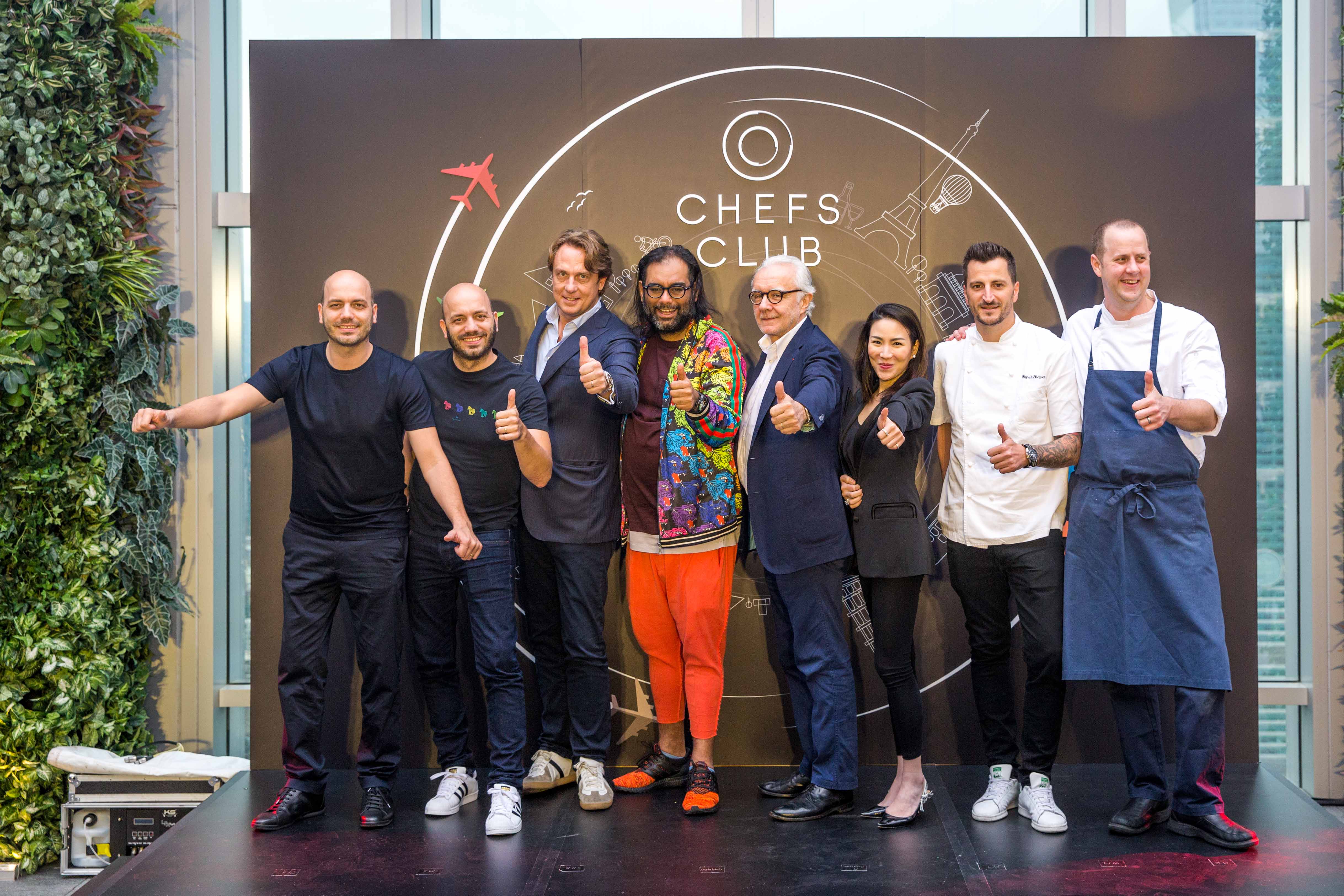 「Chefs Club Taipei」記者會上名廚齊聚一堂，入境隨俗比出大姆哥讚的手勢站台。（由左至右：「Sühring」德國雙胞胎主廚Mathias Sühring、Thomas Sühring、「Chefs Club」創辦人Stephane De Baets、「Gaggan」主廚Gaggan Anand、「法國世紀廚神」Alain Ducasse、Chefs Club亞洲營運總監MJ、杜卡斯得意門生Wilfrid Hocquet、美國名廚Matthew Kirkley。）