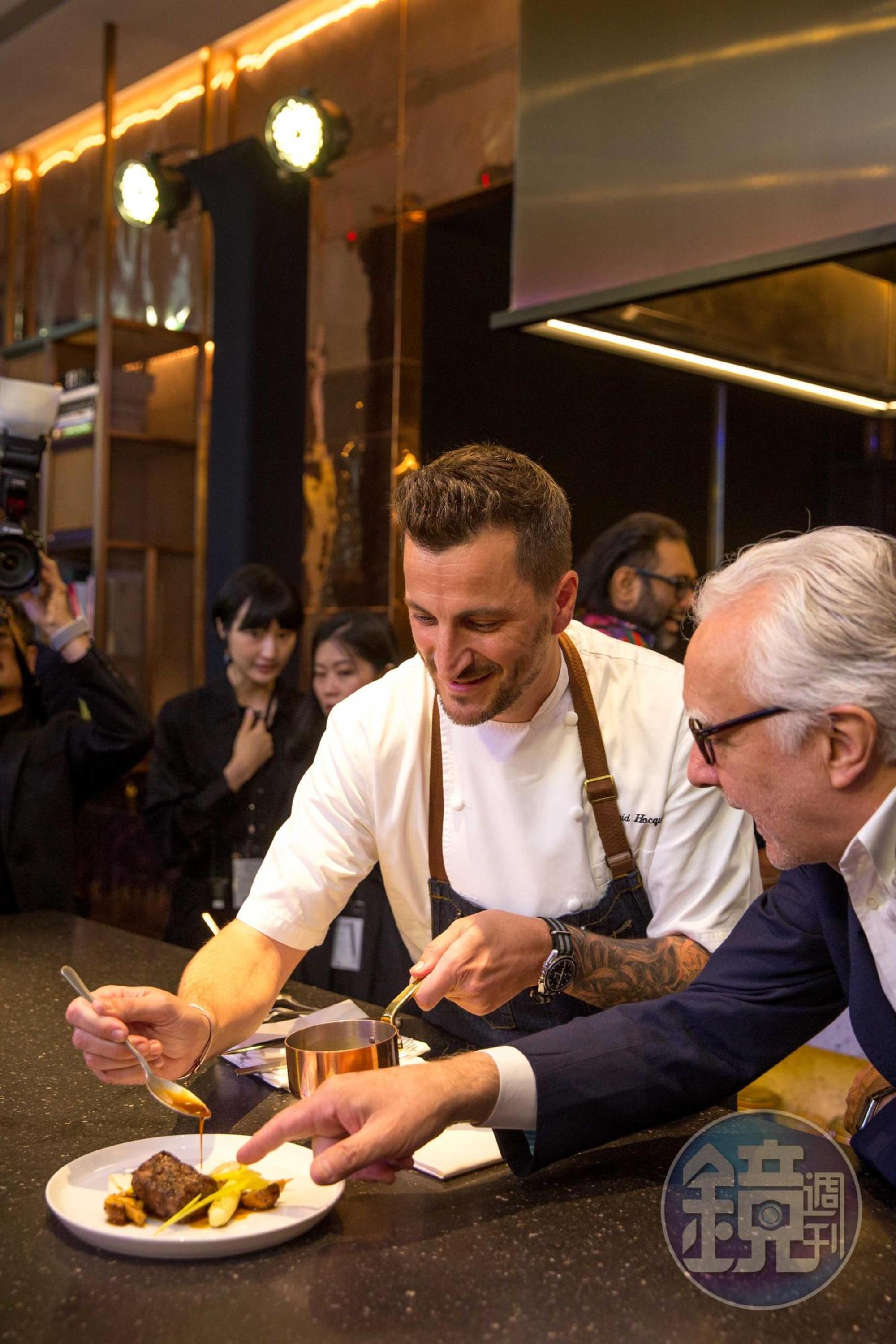 「Chefs Club Taipei」首位客座主廚Wilfrid Hocquet（左）展演菜色時，師父杜卡斯（右）在旁指點。