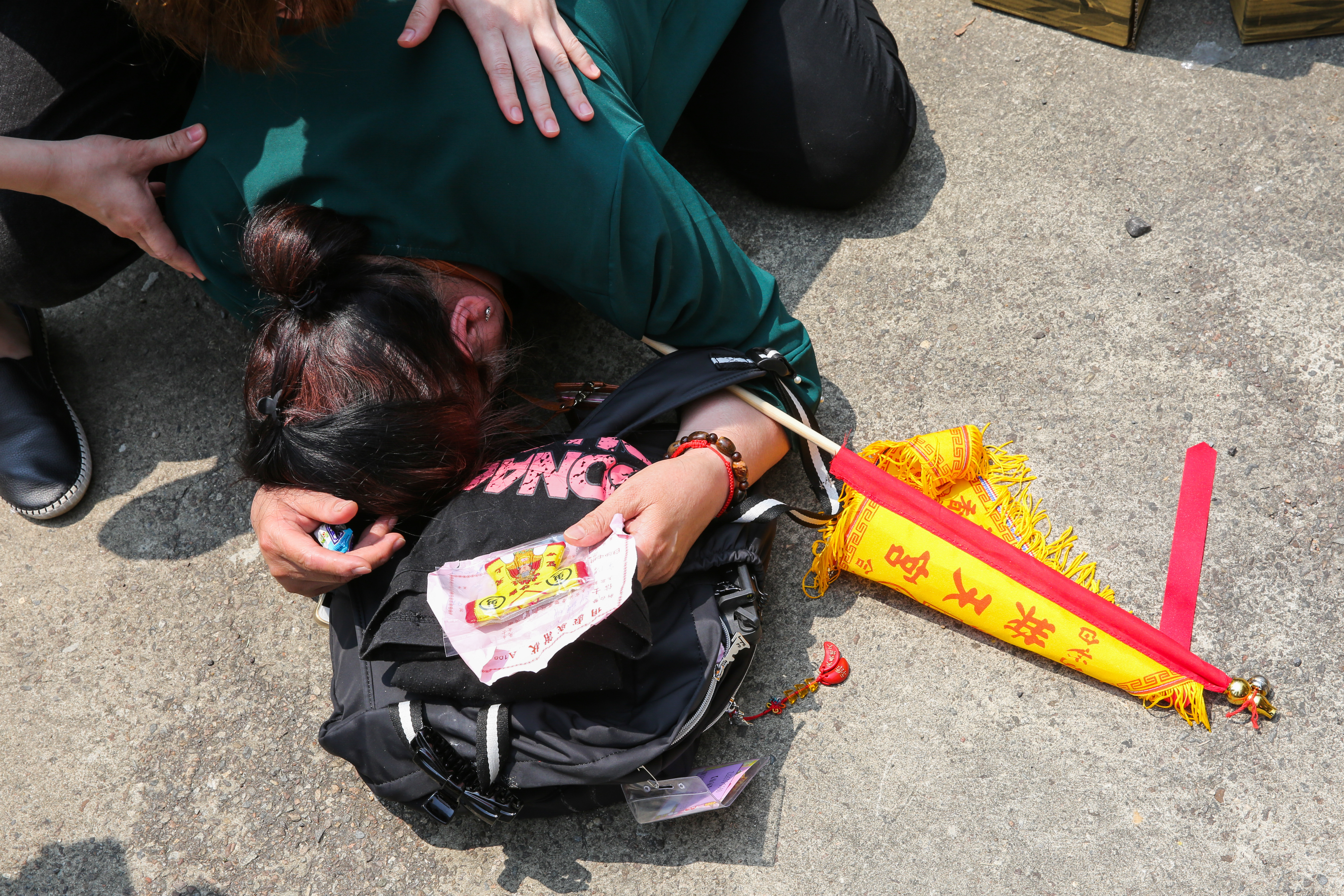 中午炎熱下,一位虔誠跪拜祈求的信徒暈倒,旁邊人上前攙扶。