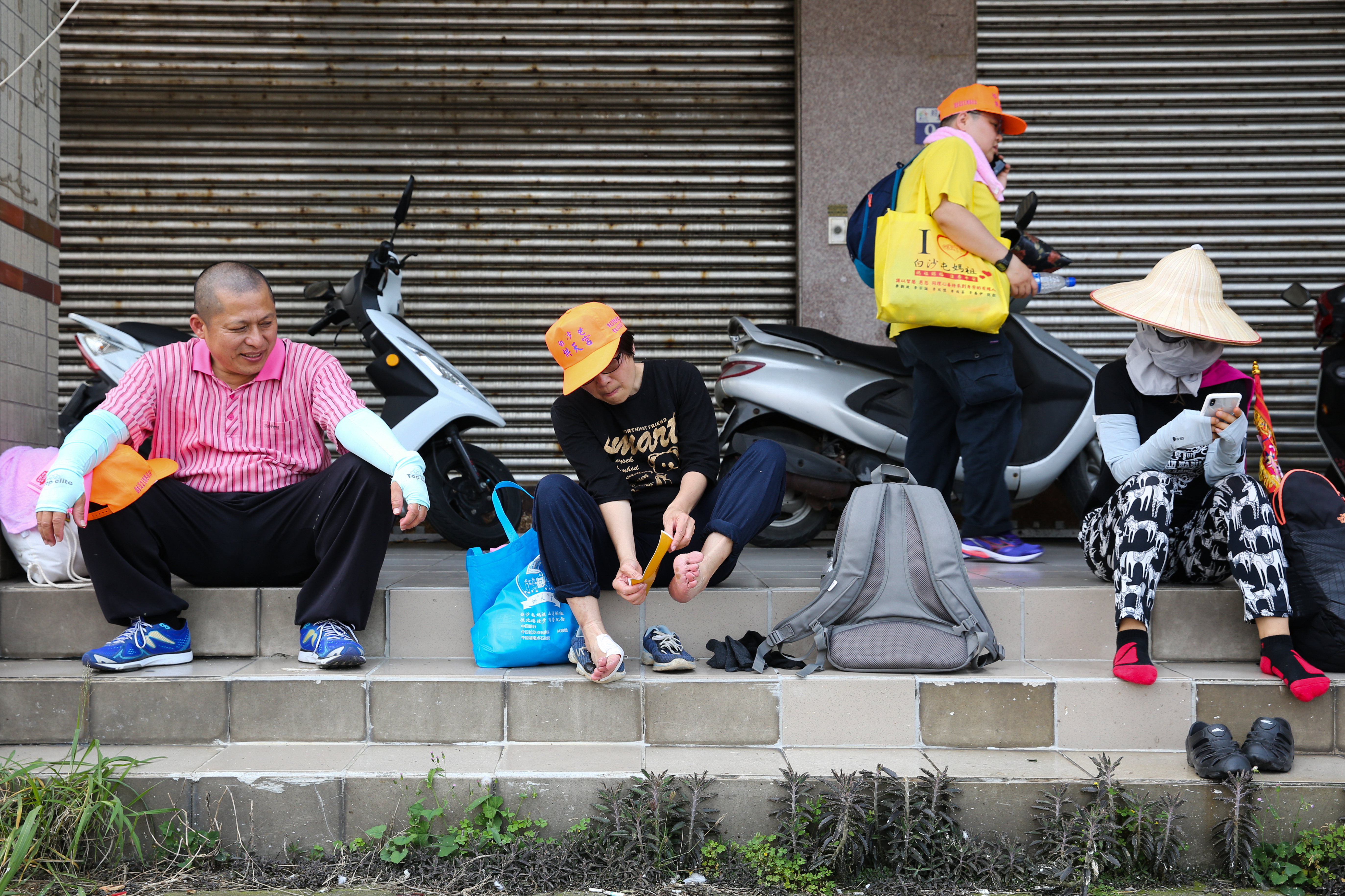 經過一晚的長途跋涉,路邊民眾拿出沿途發送的結緣貼布緩解腳底酸痛。