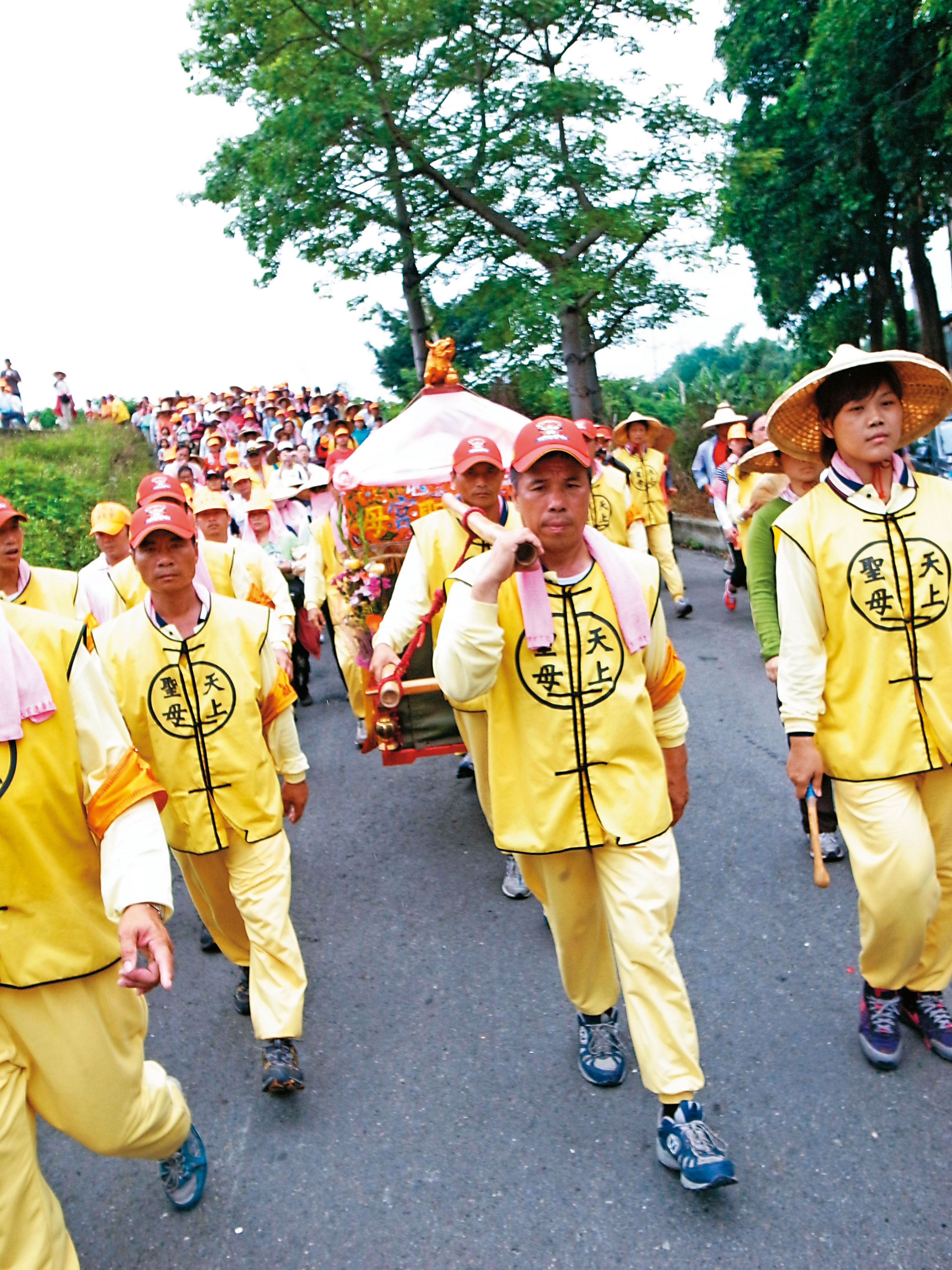 陳弼宏(前方扛轎者)擔任轎班長達30年,他說穿上制服般的黃背心就不能講話,休息時,上廁所或抽菸,都必先脫下背心。(方麗雯提供)