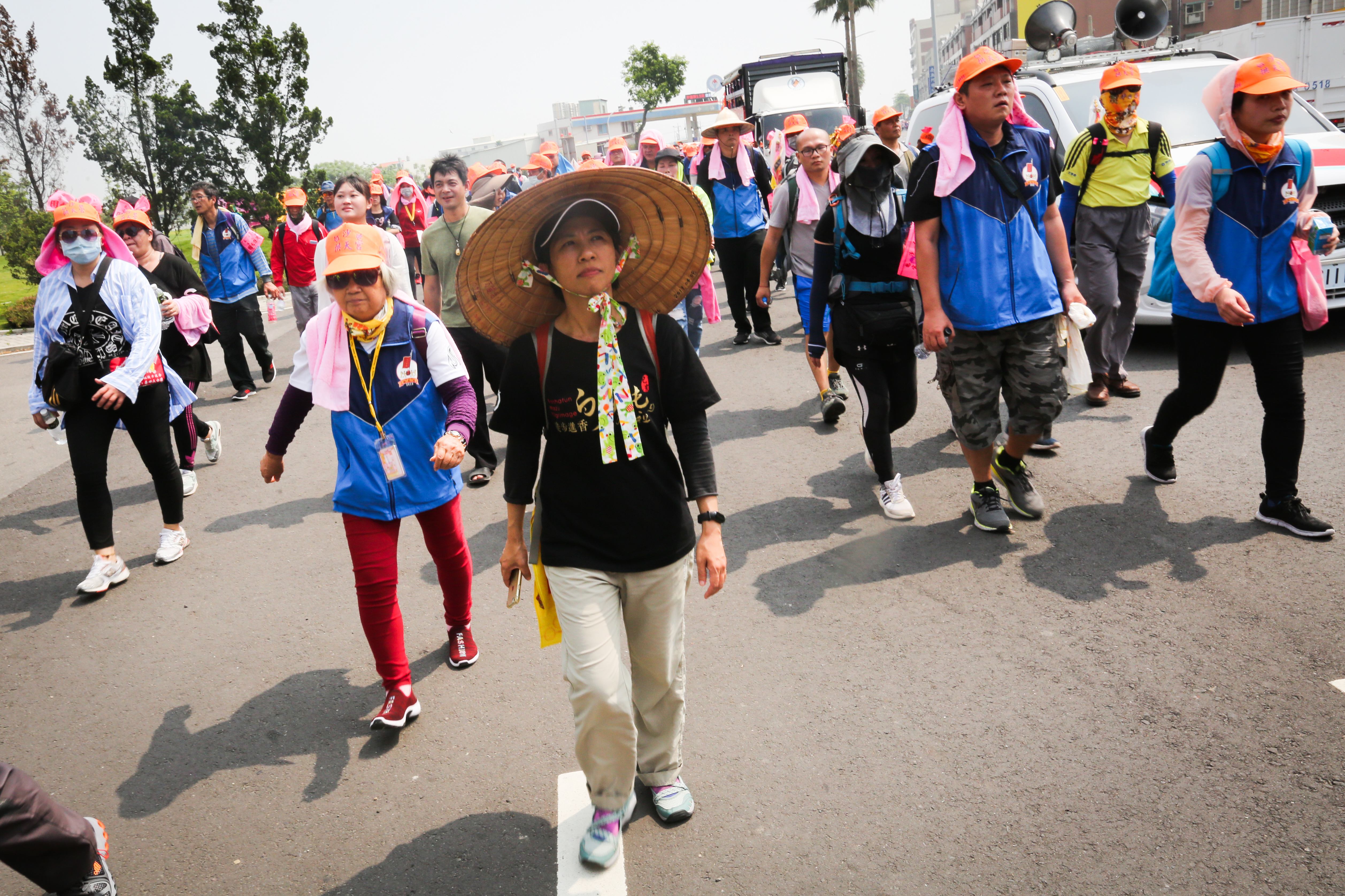今年是方麗雯（戴斗笠者）第11年進香，身為年刊總編的她，一路上除了走，還幫我們調照片，為了白沙屯報導的正確性，反覆和記者確認細節。