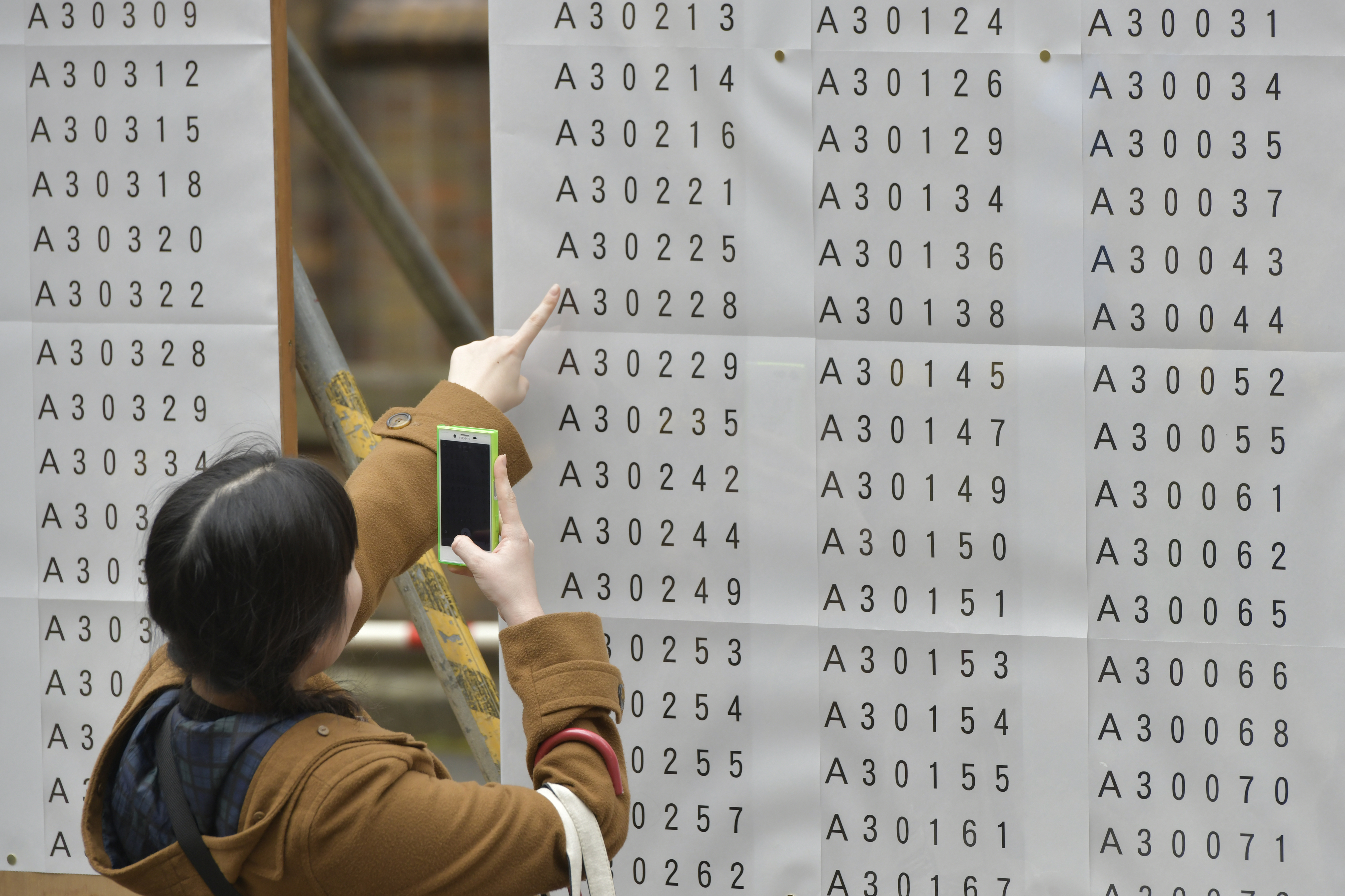 日本正往免費大學教育的目標努力。圖為今年度東京大學入學考試時,準考生尋找自身號碼一景。(東方IC)