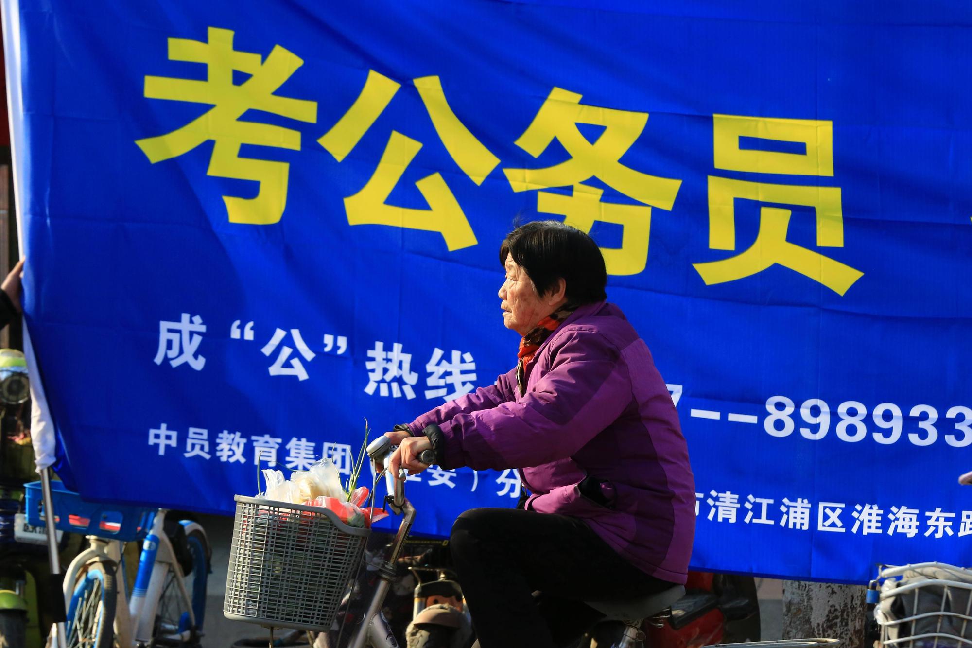 2019年3月，中國江蘇淮安師院附中考場外醒目的公務員考試補習班招生廣告。中國公家單位職務一向被視為「鐵飯碗」甚至「金飯碗」。江蘇省今年招錄6507人，報考人數近32萬人。（東方IC）