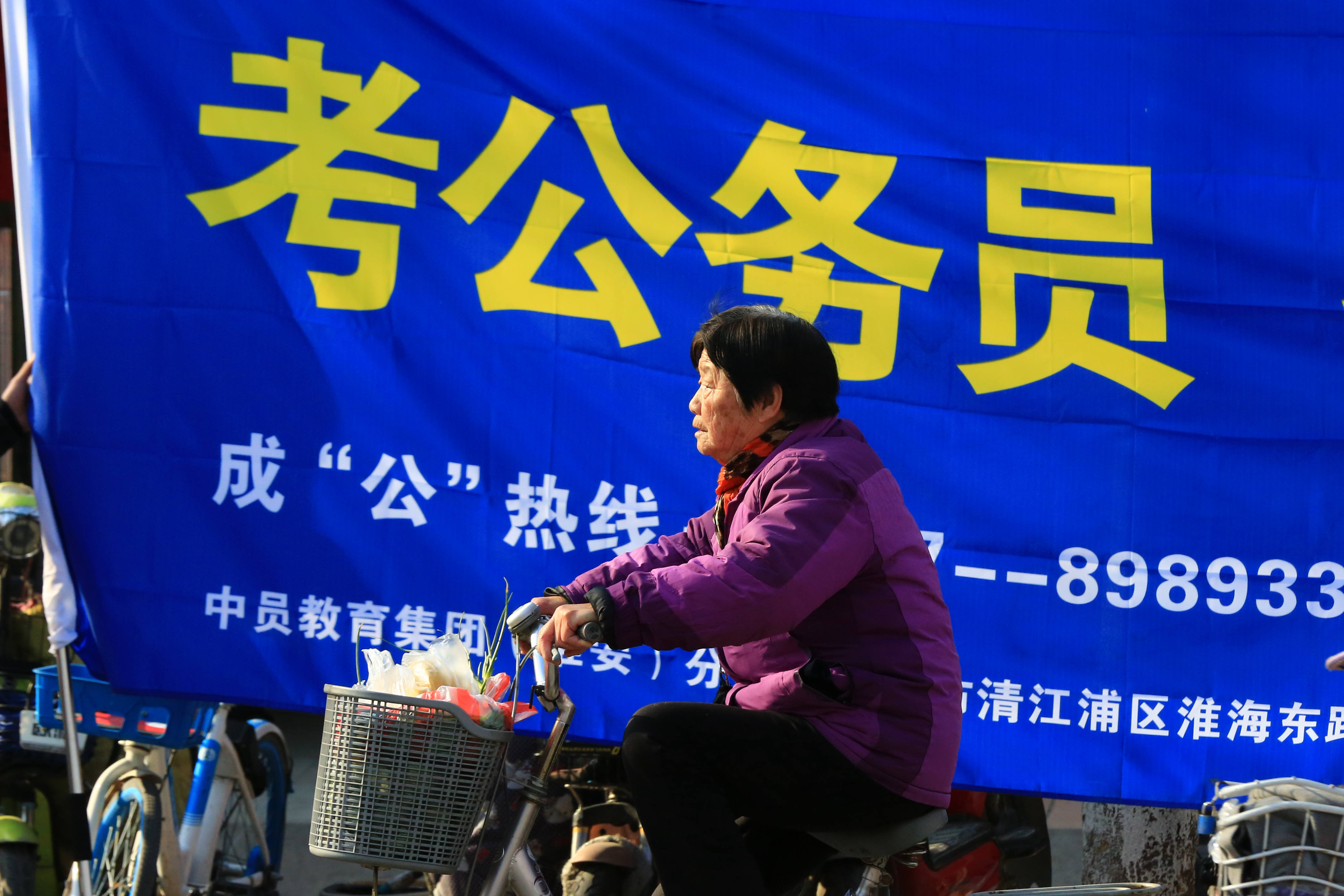 2019年3月，中國江蘇淮安師院附中考場外醒目的公務員考試補習班招生廣告。中國公家單位職務一向被視為「鐵飯碗」甚至「金飯碗」。江蘇省今年招錄6507人，報考人數近32萬人。（東方IC）