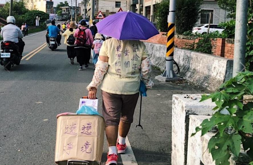 大甲媽祖遶境每年進香活動都吸引上萬信眾跟隨，一位媽媽一面推著車，邊將路上垃圾收拾乾淨。（翻攝島內散步臉書粉絲頁）