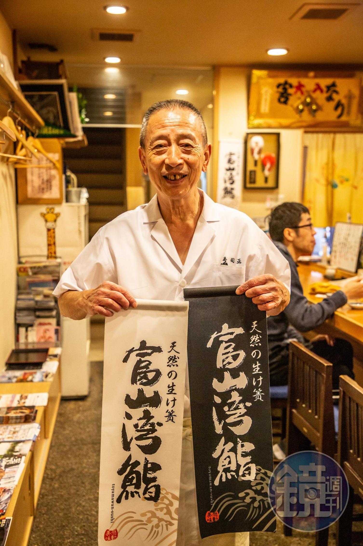 「江戶前壽司正」老闆熱情拿著印有「富山灣鮨」的掛旗。