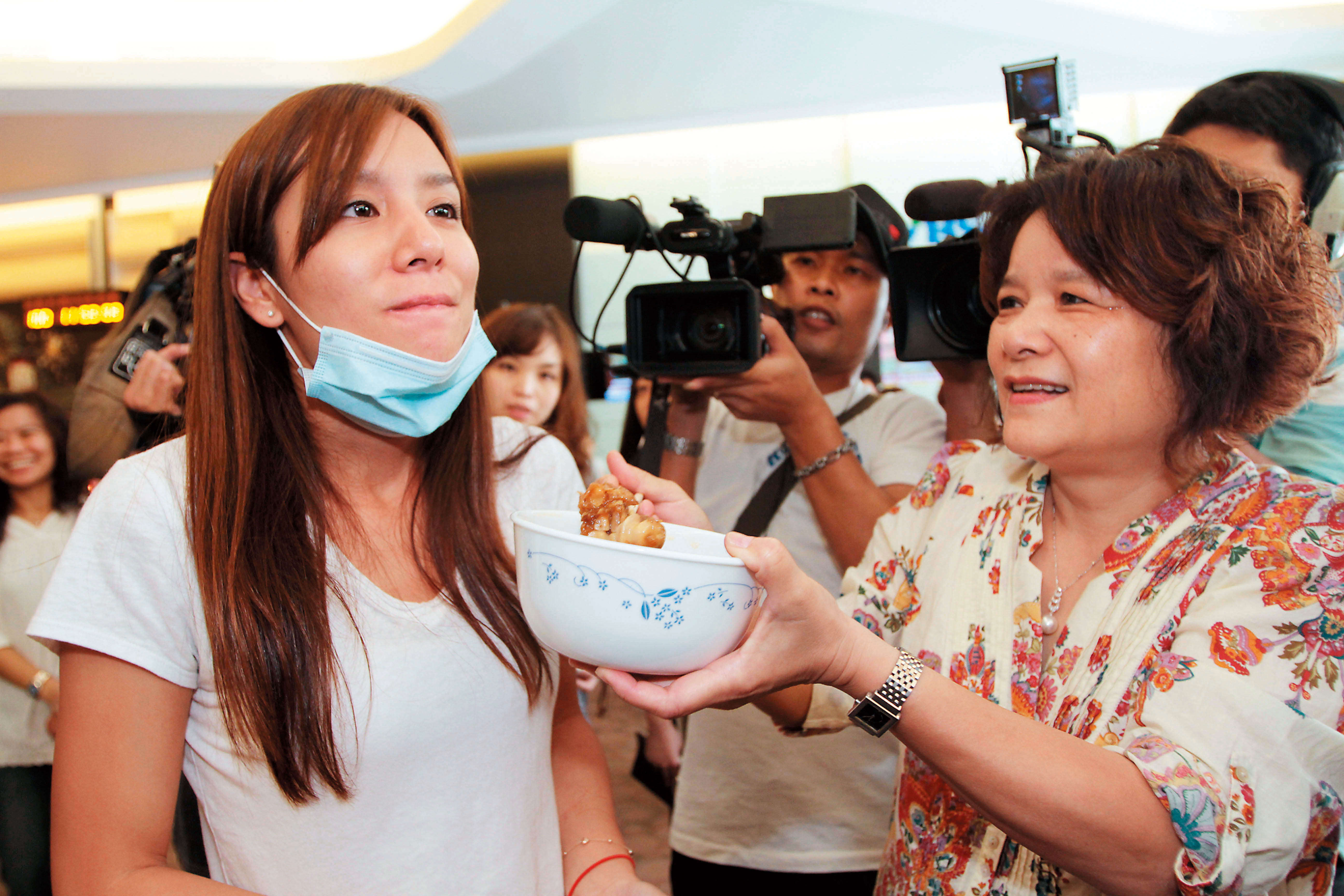 2010年前往印度拍攝外景，意外遭遇槍擊掃射，急忙提前返台，媽媽（右）特別在機場餵莎莎吃豬腳麵線。（東方IC） 