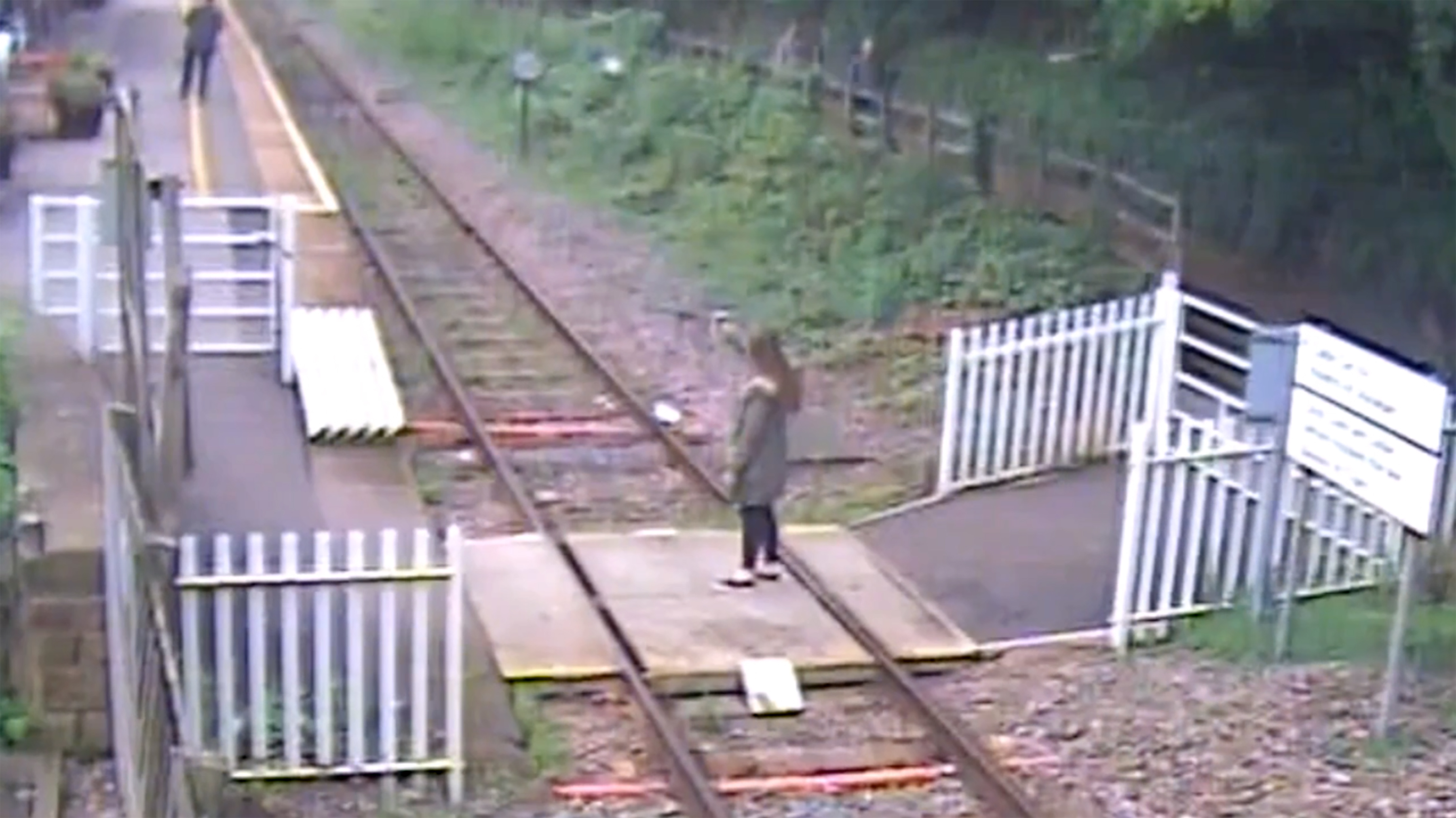 英國德比郡一名女子在平交道鐵軌上自拍，被監視器錄下。（東方IC）