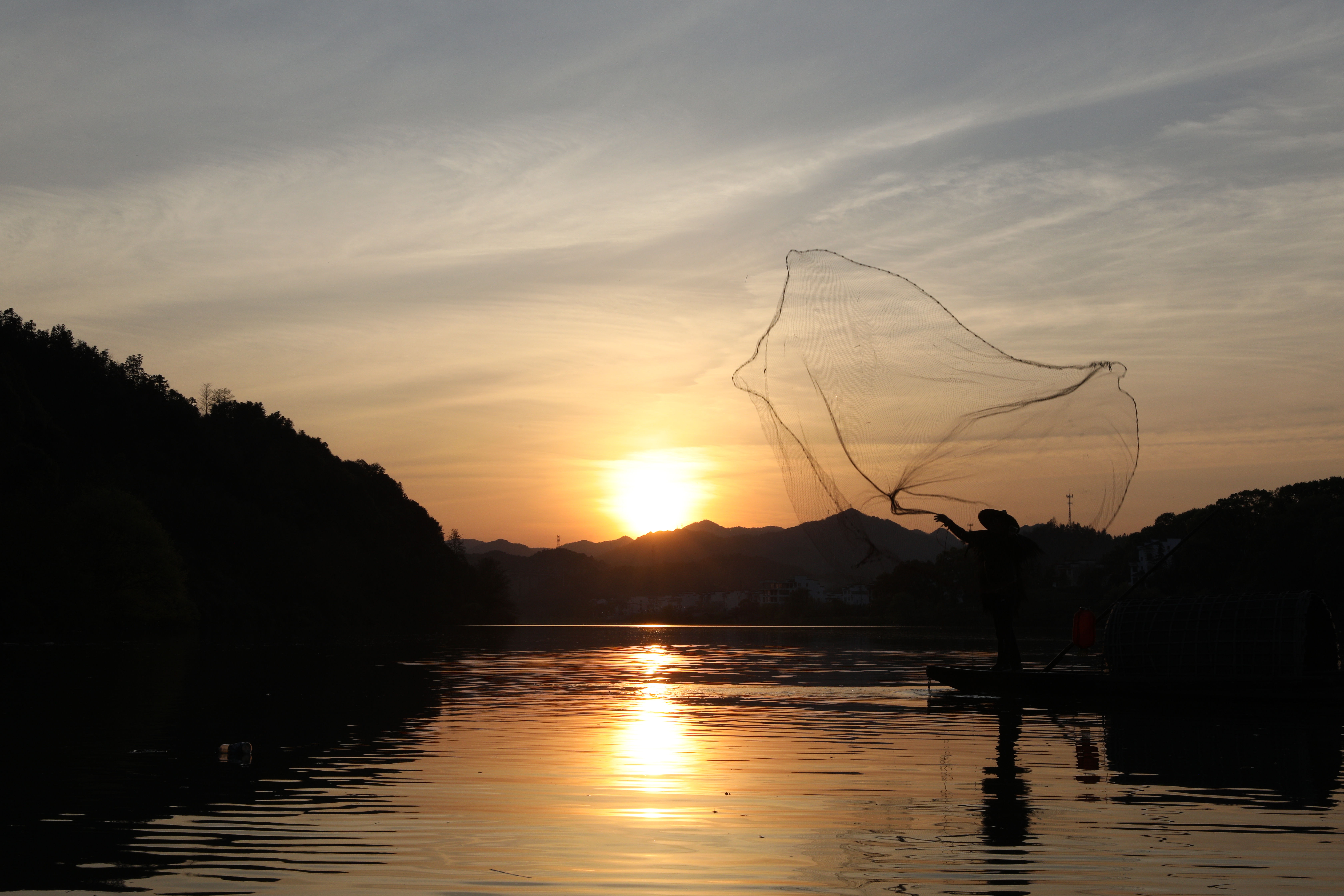 在落日餘暉下，欣賞漁夫撒網捕魚，是月亮灣的美麗風景。