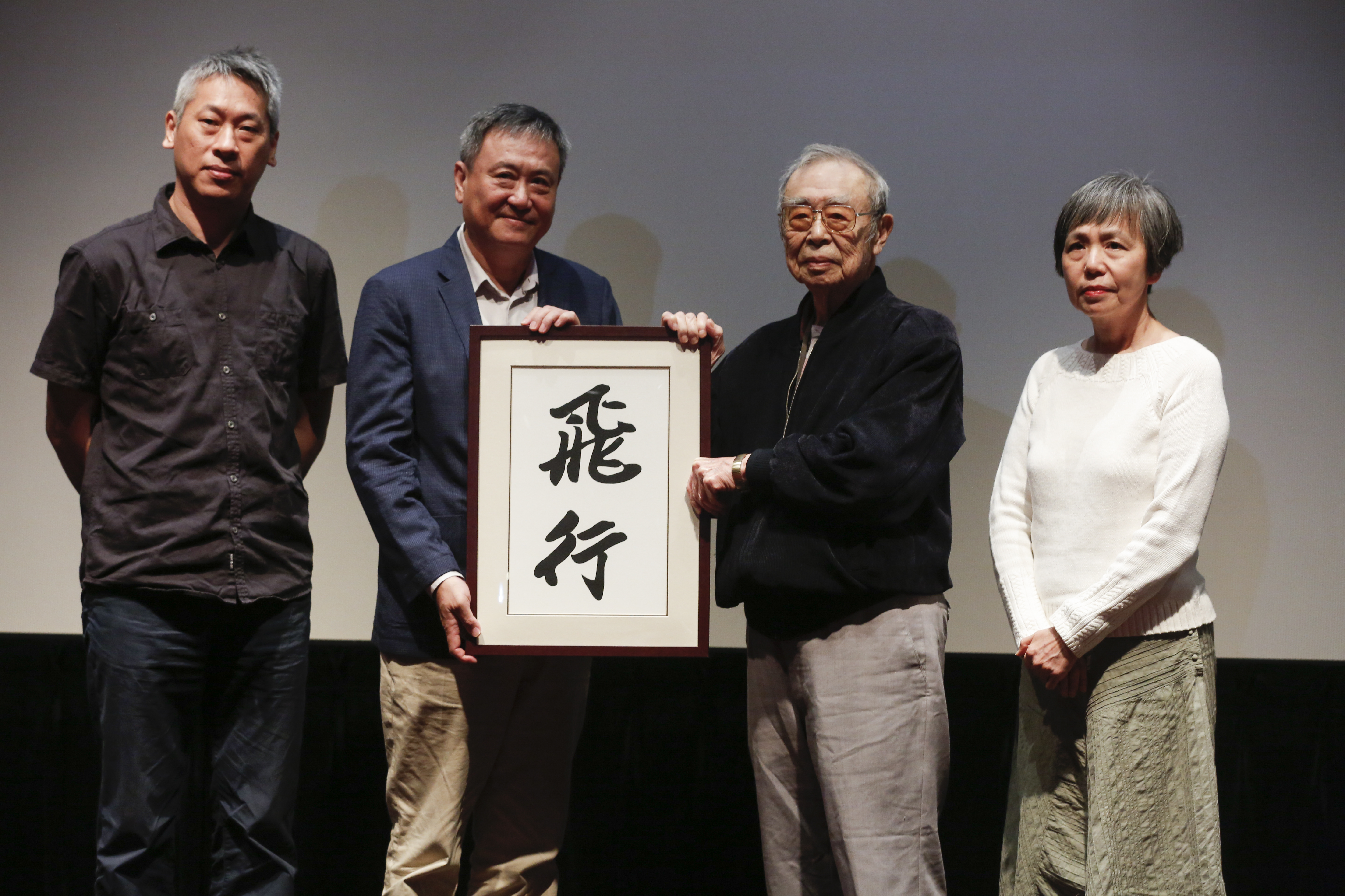 《尋找1920》紀錄片首映,導演許明淳(左起)、李崗監製、謝東漢、謝安莉手持由謝文達手寫「飛行」二字的復刻書法。