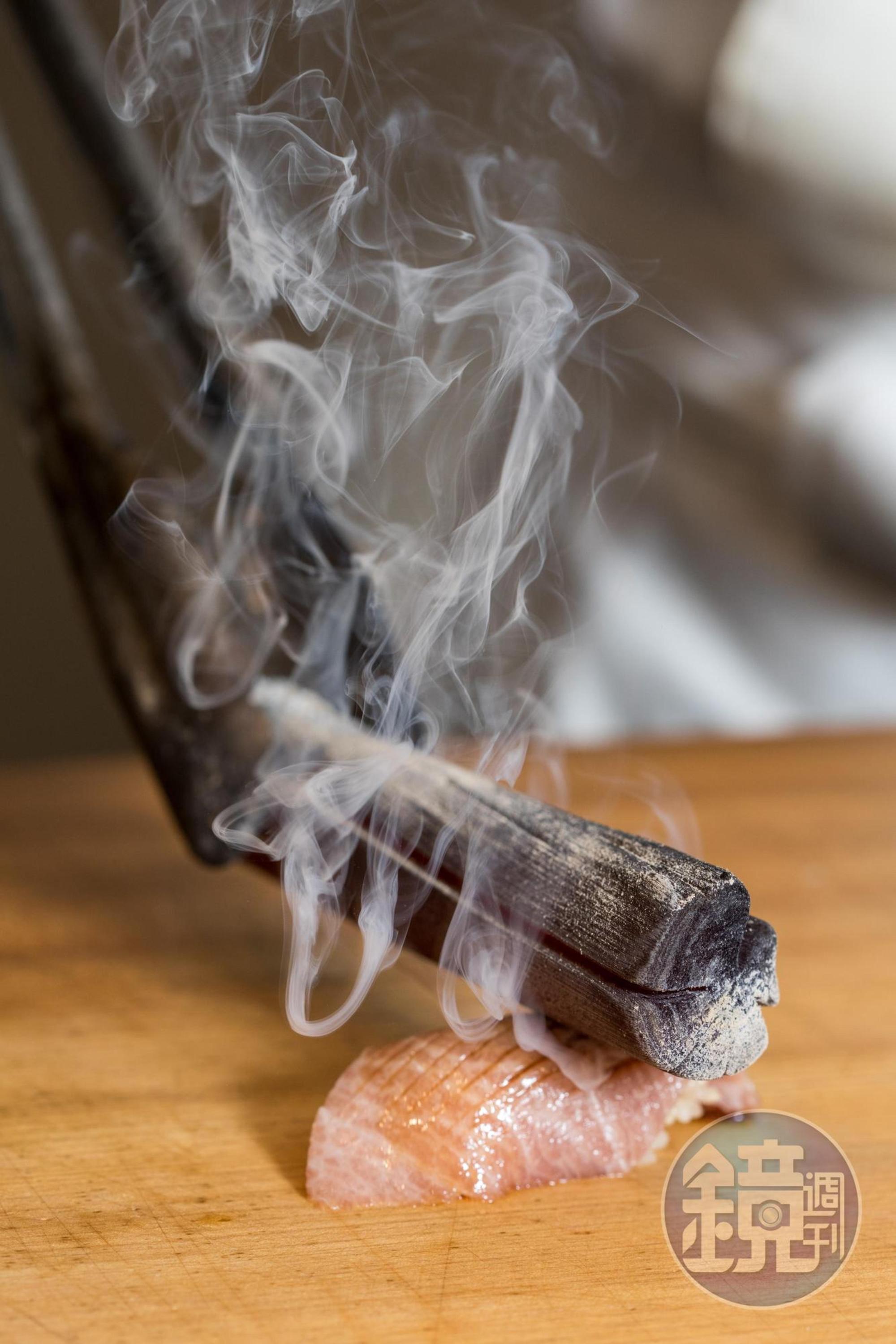 以燒燙的備長炭炙烤黑鮪魚，現場煙霧竄升，很有戲劇效果。