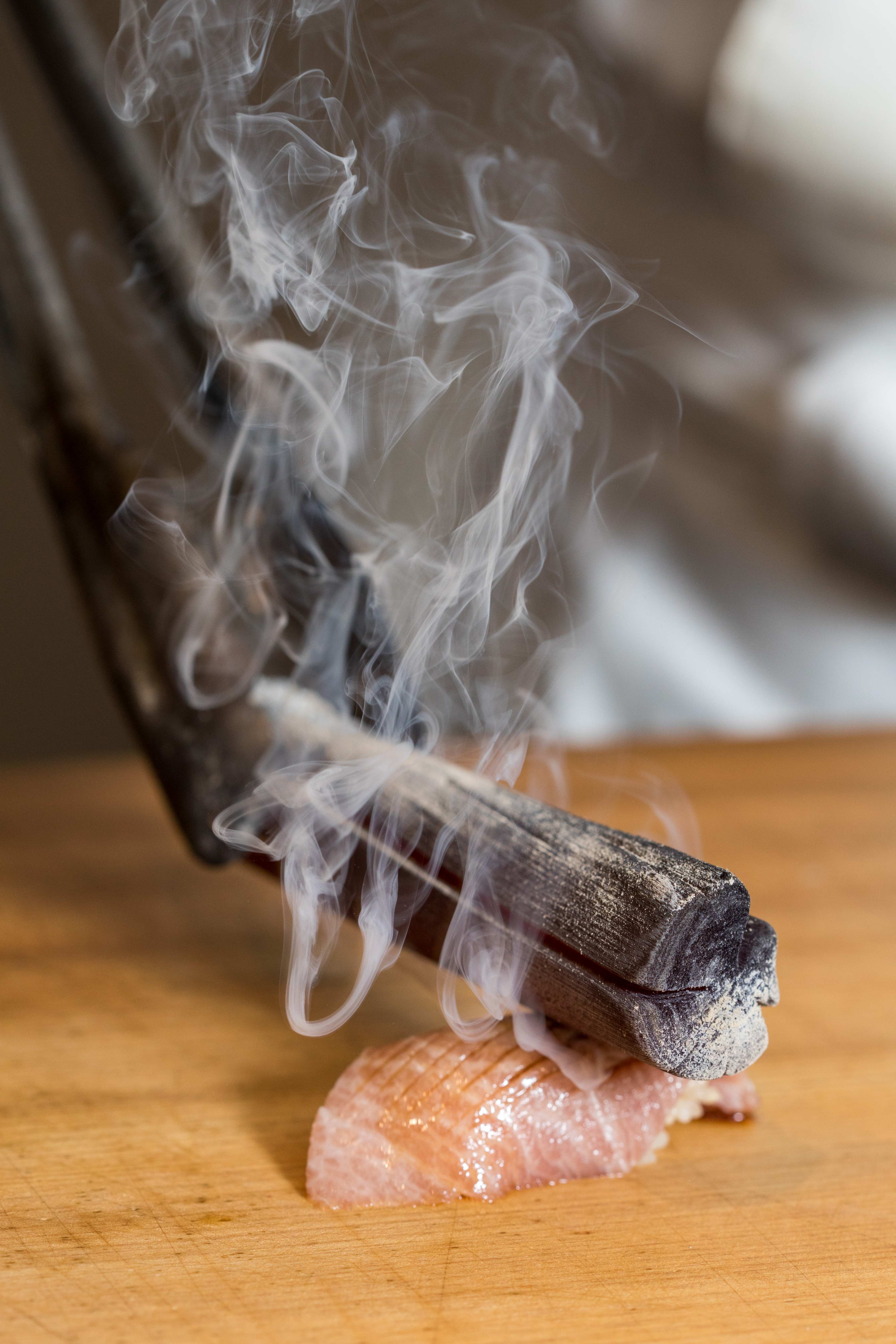 以燒燙的備長炭炙烤黑鮪魚，現場煙霧竄升，很有戲劇效果。