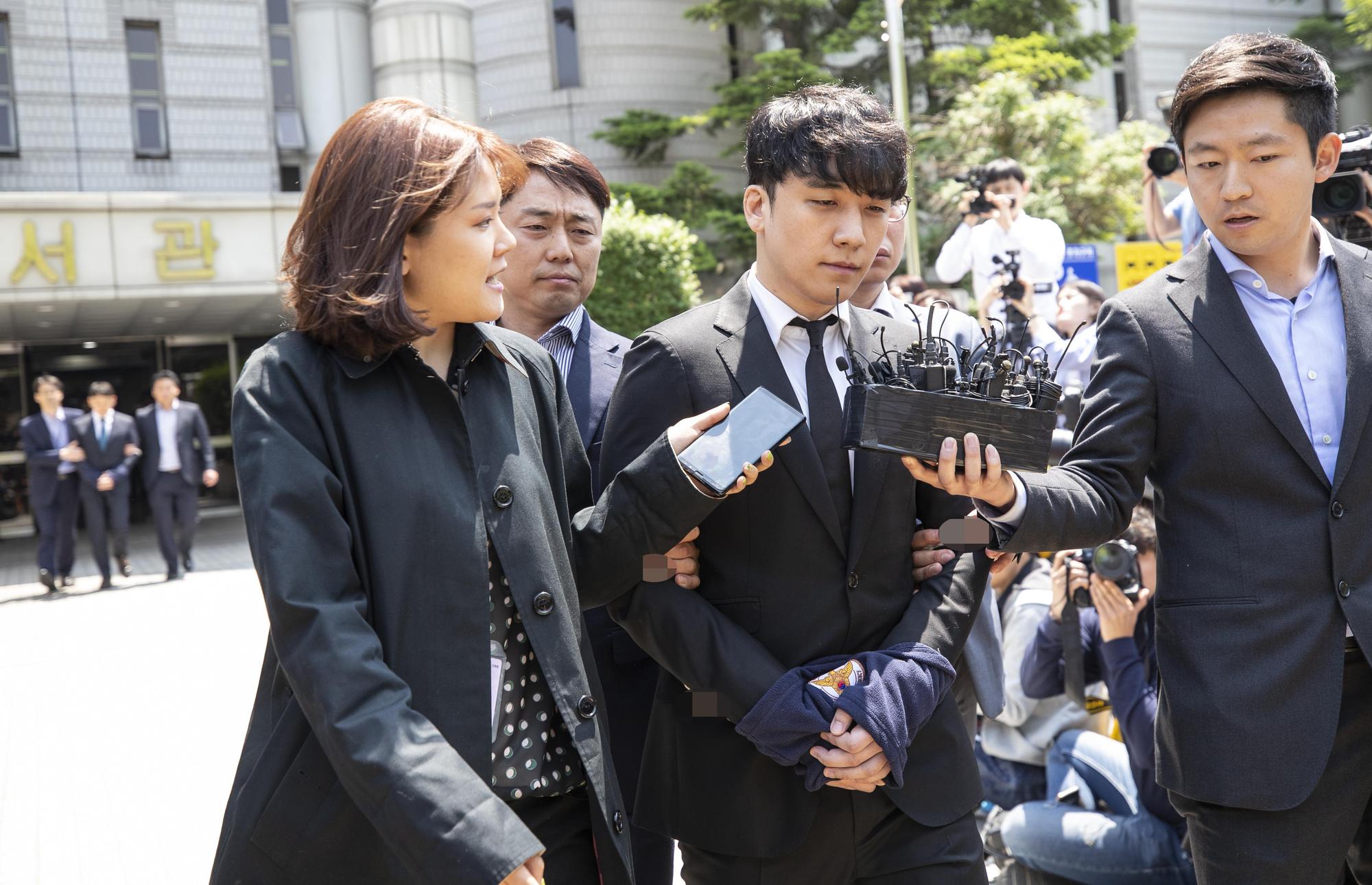 勝利涉及4項罪名被上警繩手銬,隨警察走出首爾中央地方法院移送看守所。(東方IC)