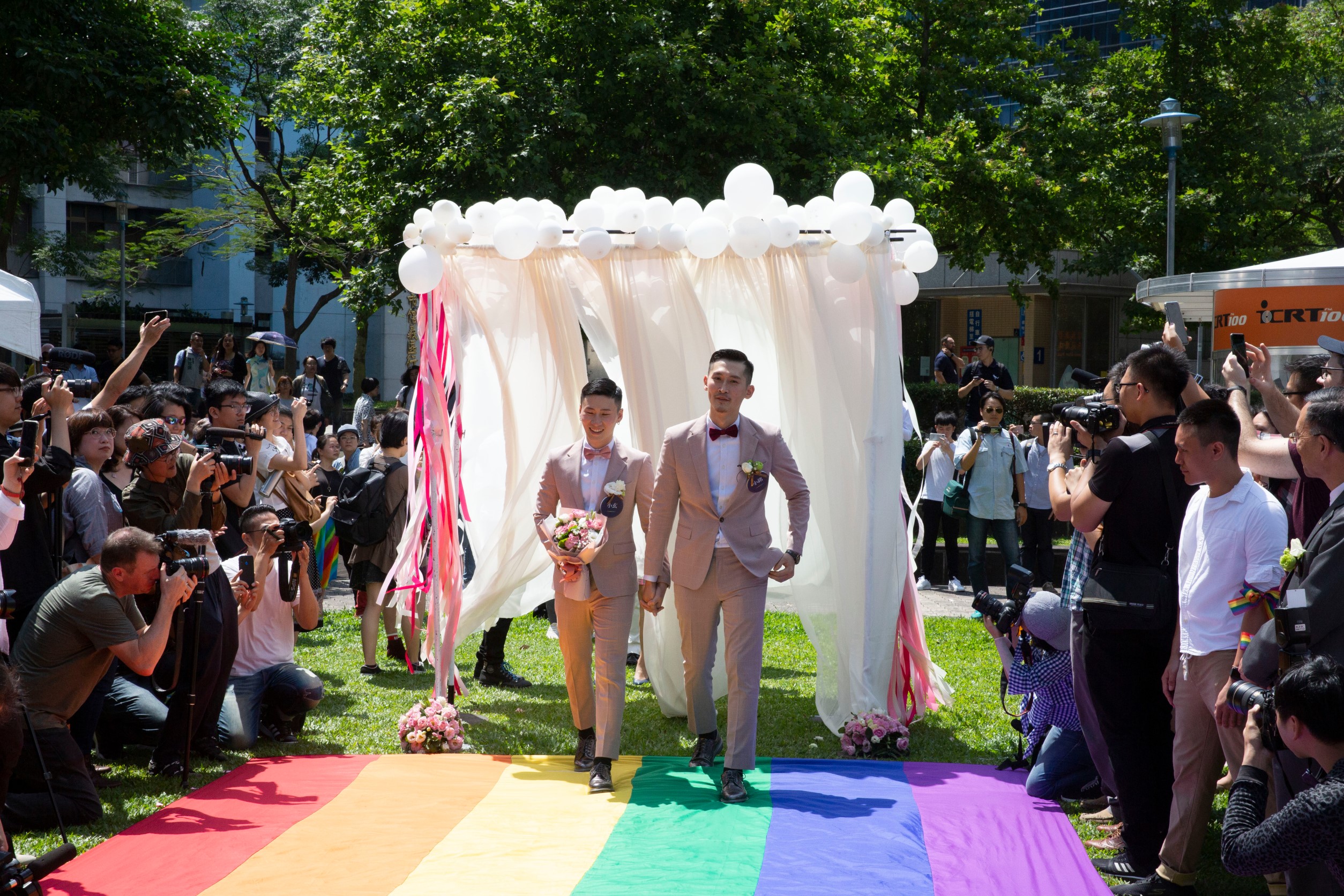 今（24日）於信義區戶政事務所進行登記的小銘與小玄在眾人祝福下，一同走過彩虹旗慶祝新婚。