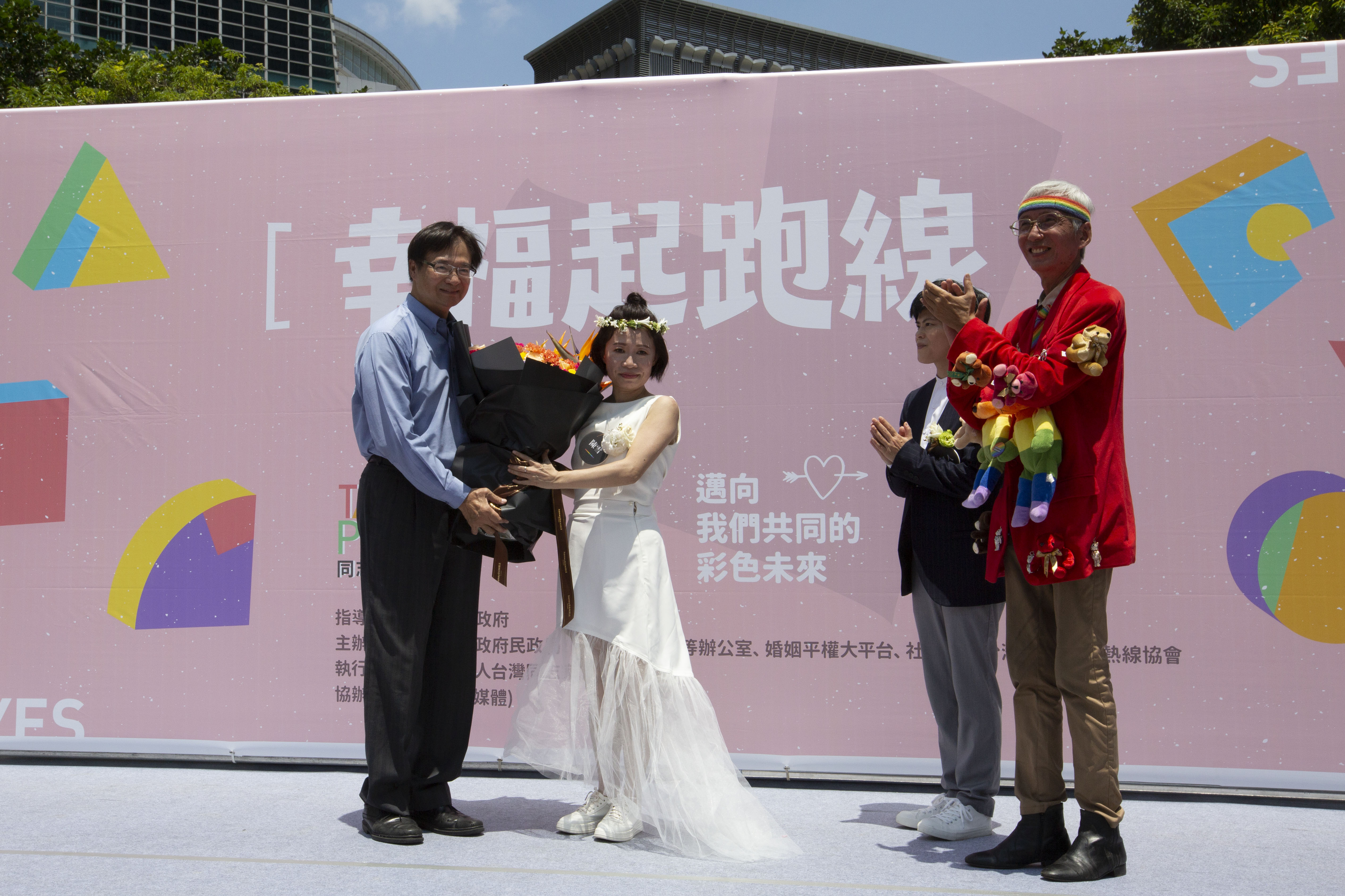 作家陳雪（左二）與伴侶早餐人（右二）辦理結婚登記，北市由民政局長藍世聰（左一）送花祝賀