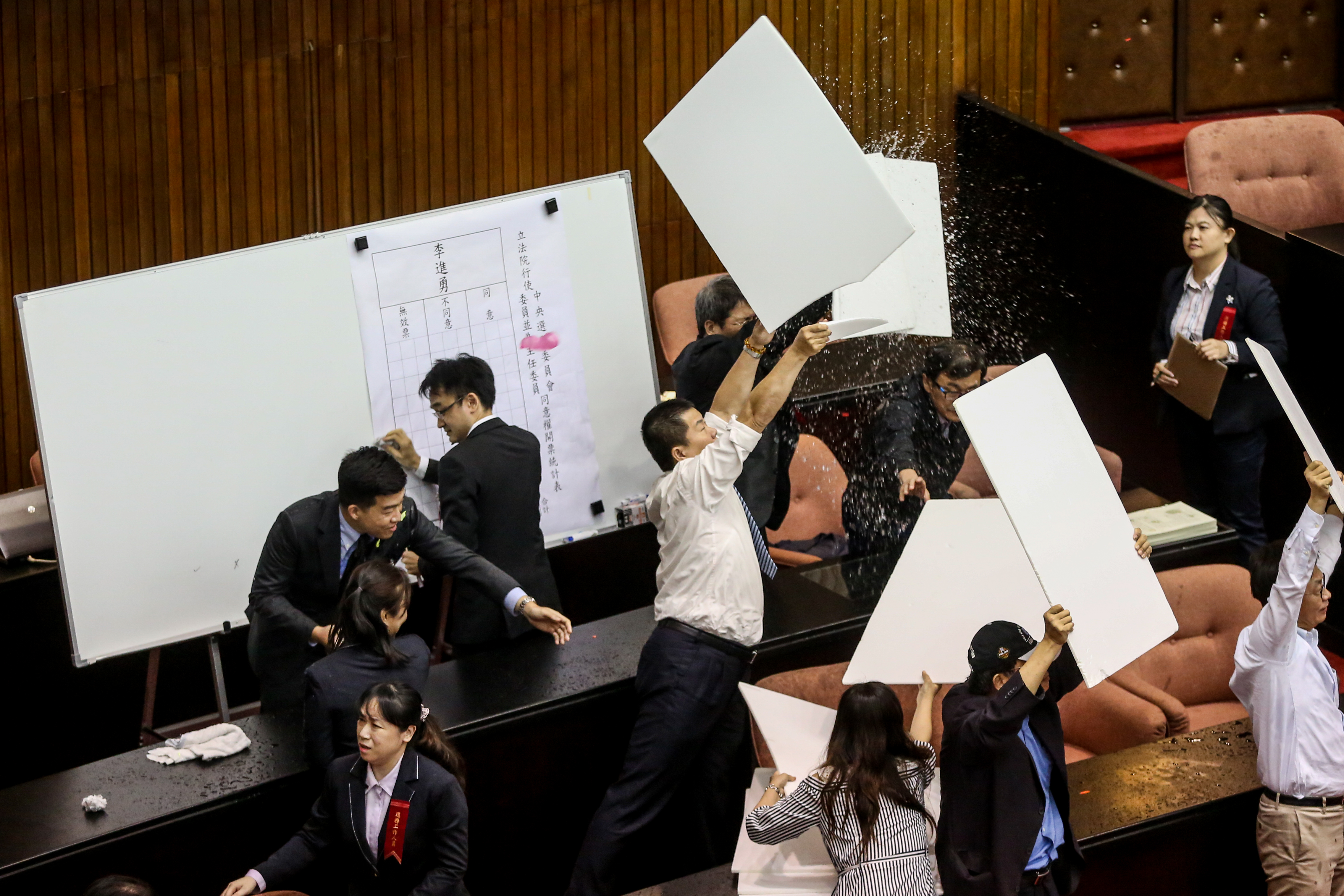 議事人員也拿起看板阻擋水球干擾開票。