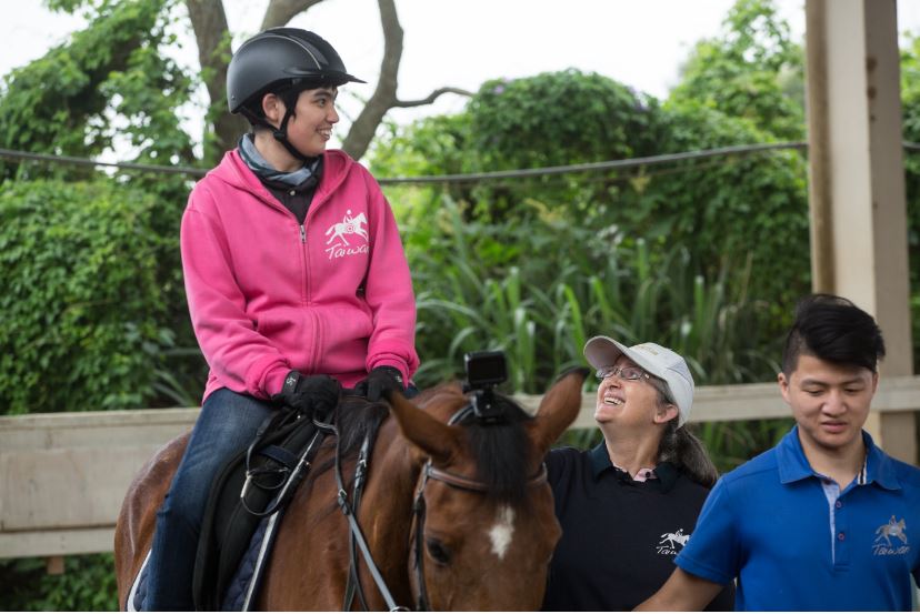 來台30多年的Uta（中）當初是為了患有腦麻的女兒安安（左）開始投入馬術治療，如今她在桃園新屋馬場的台灣馬術治療中心擔任教學顧問，是無給職。