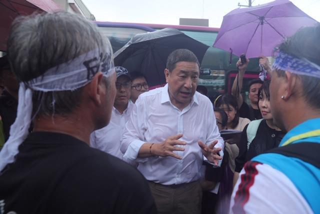 張安平親自出席「水泥業（窯）協同處理廢棄物BOO案」公聽會，並在大雨中主動和抗議村民對話。（台泥提供）