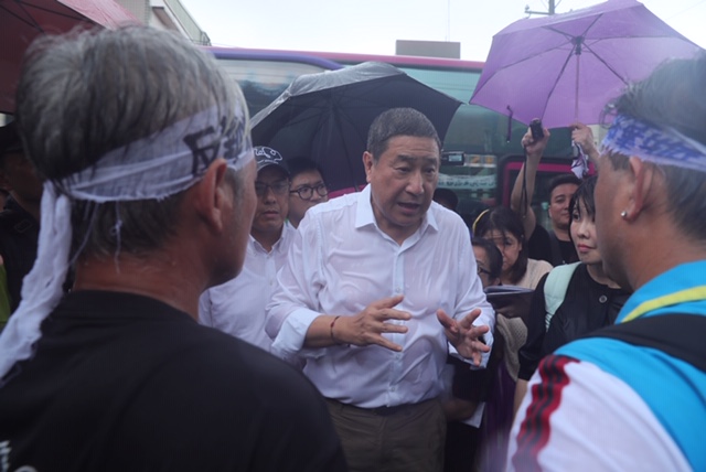 張安平親自出席「水泥業（窯）協同處理廢棄物BOO案」公聽會，並在大雨中主動和抗議村民對話。（台泥提供）