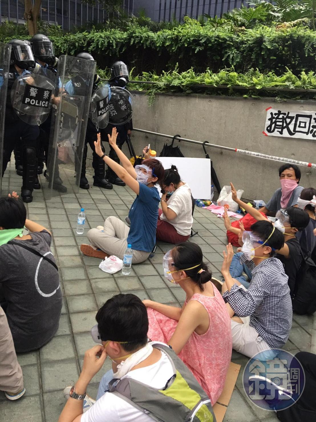 警方開始催淚彈清場後，天橋上的絕食群眾堅持坐在原地，舉手和平示威。