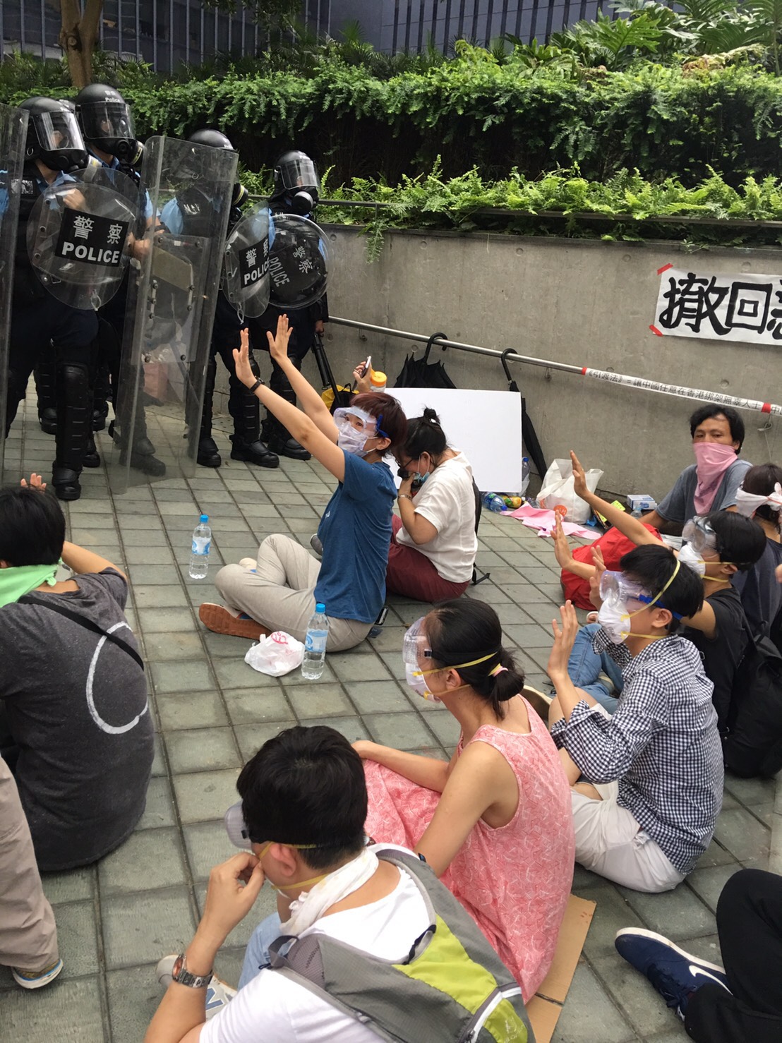 警方開始催淚彈清場後，天橋上的絕食群眾堅持坐在原地，舉手和平示威。