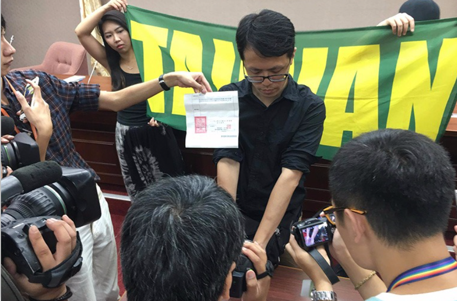 陳姓民眾對遭憲兵不表明身分沒收旗幟抬離世大運現場表達不滿,當時還曾召開記者會。(翻攝蠻番島嶼社臉書)