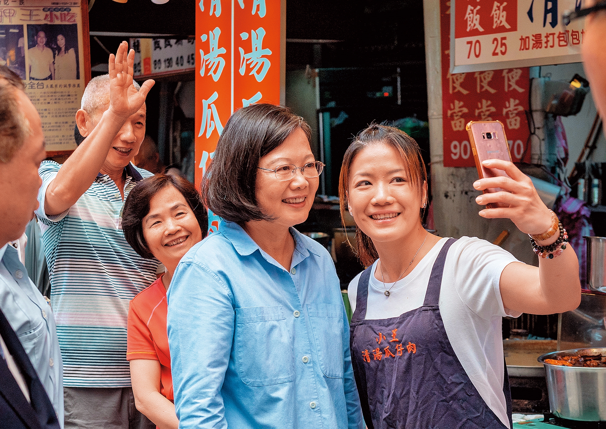 蔡英文（前左）在初選期間成功塑造「辣台妹」形象，支持度回溫，圖為蔡英文16日走訪台北萬華華西街，熱情攤商拿出手機與蔡自拍。（總統府提供）