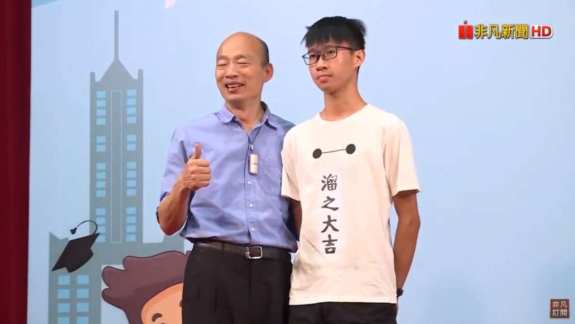 黃同學穿著「溜之大吉」T恤上台與韓國瑜合照,希望市長不要去選總統。(翻攝自USTV 非凡電視YouTube頻道)