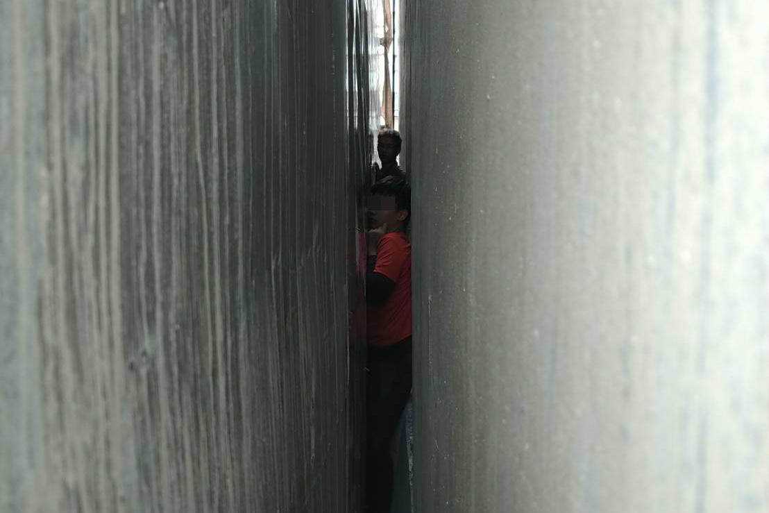 13歲男童因好奇卡進兩屋間僅15公分的縫隙，動彈不得。（翻攝照片）