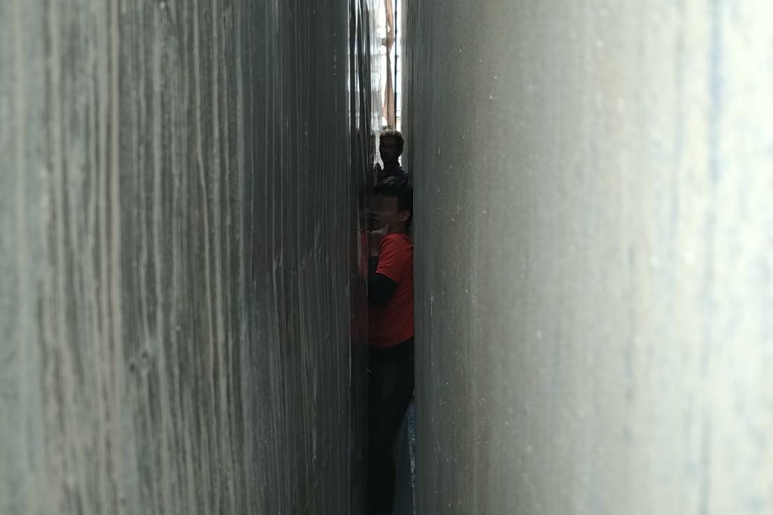 13歲男童因好奇卡進兩屋間僅15公分的縫隙，動彈不得。（翻攝照片）