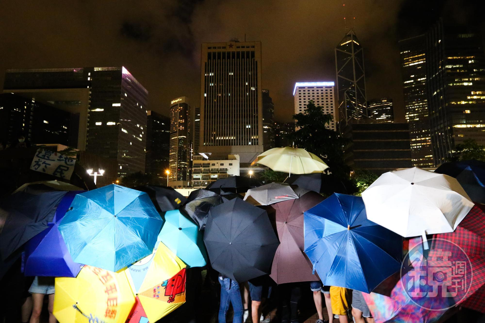解放軍駐港部隊前民眾撐起傘，等候警方的下一步行動。