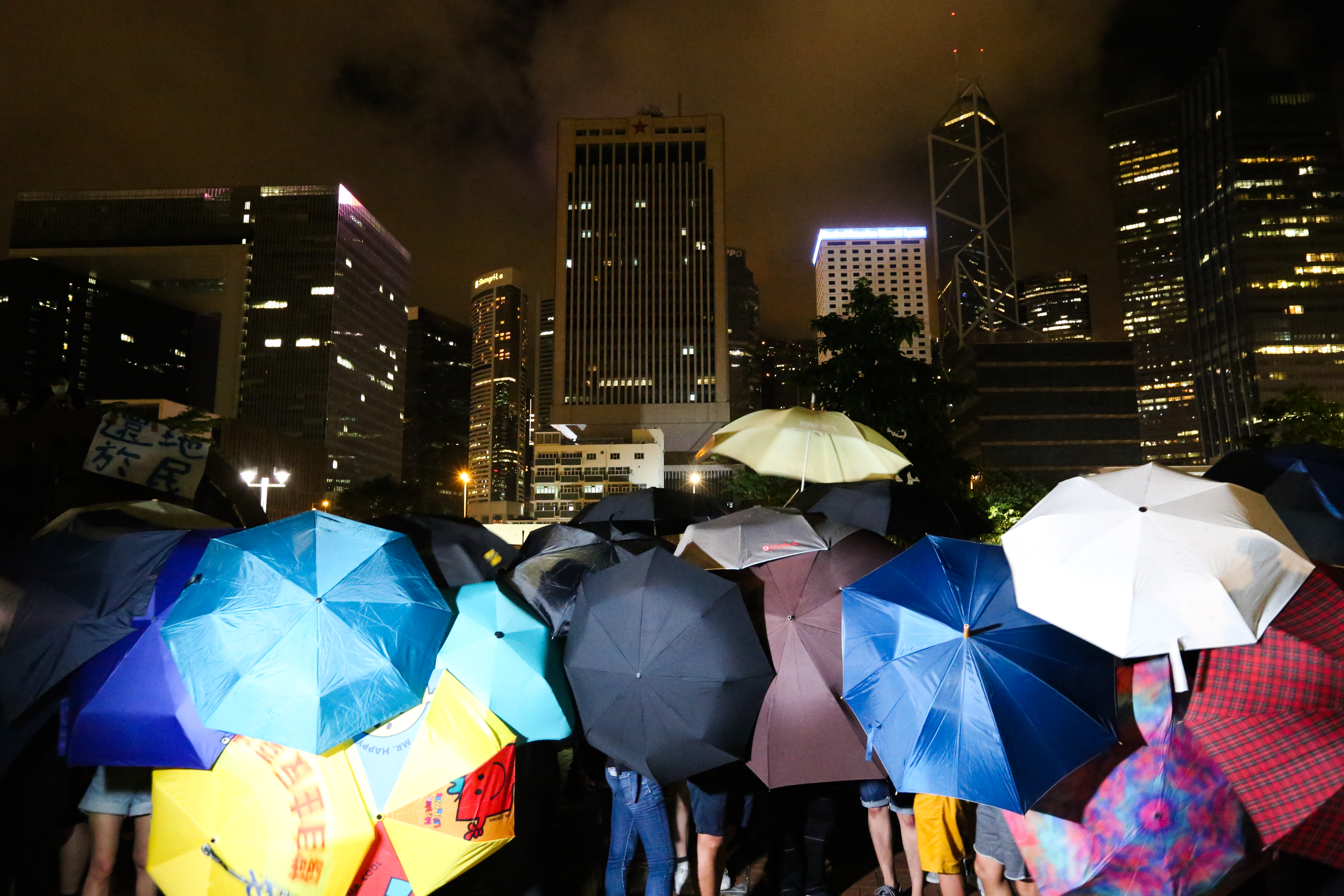 解放軍駐港部隊前民眾撐起傘,等候警方的下一步行動。