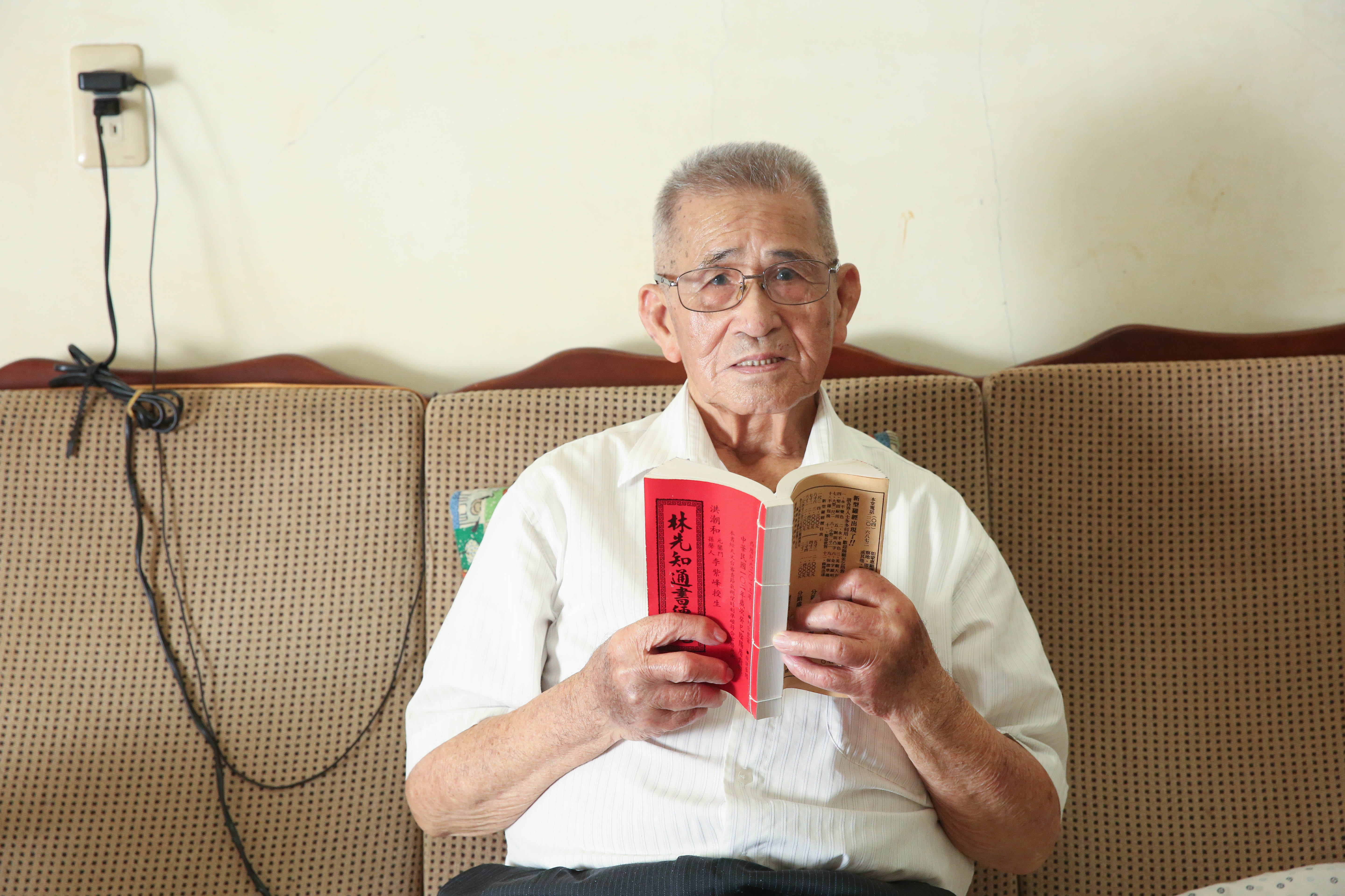 張金德手持的紅皮「通書」是從事風水、修墓工作者必備的「工具書」。他現已退休，改信基督教。