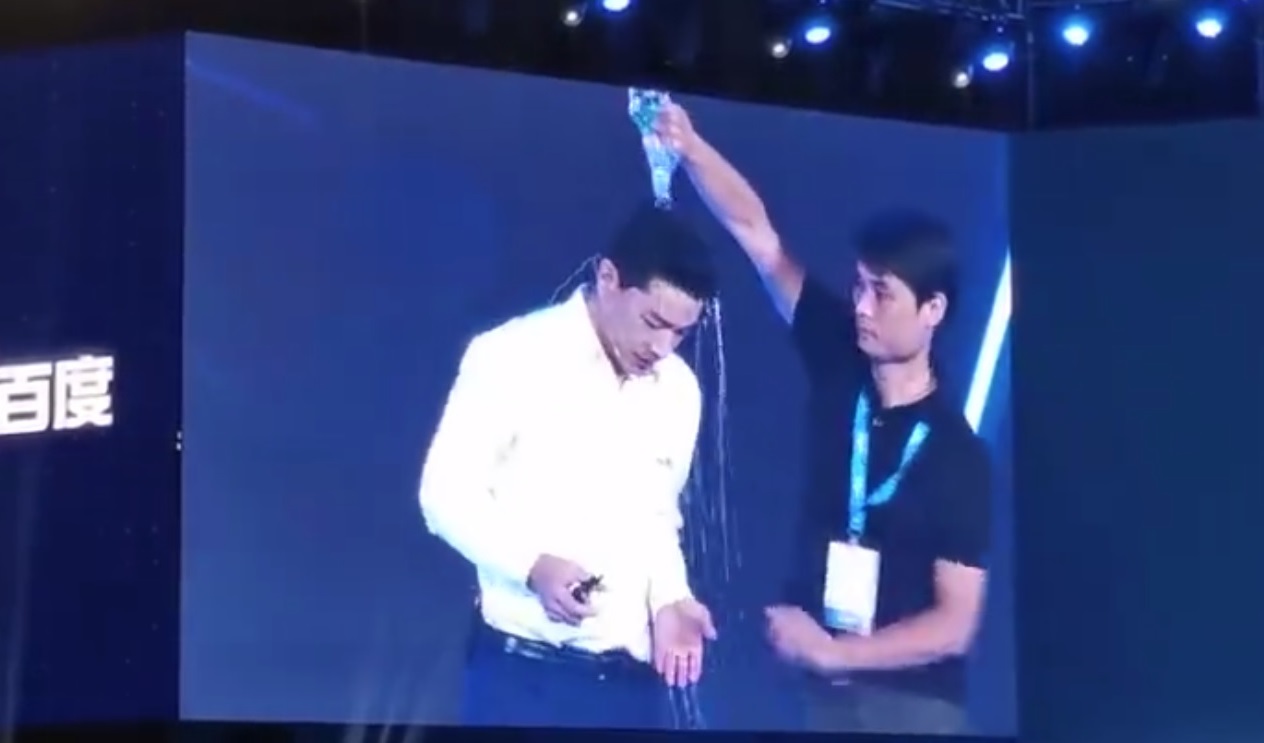 百度董事長李彥宏昨（3日）上台演講時，遭黑衣男子衝上台潑水。（翻攝自微博）