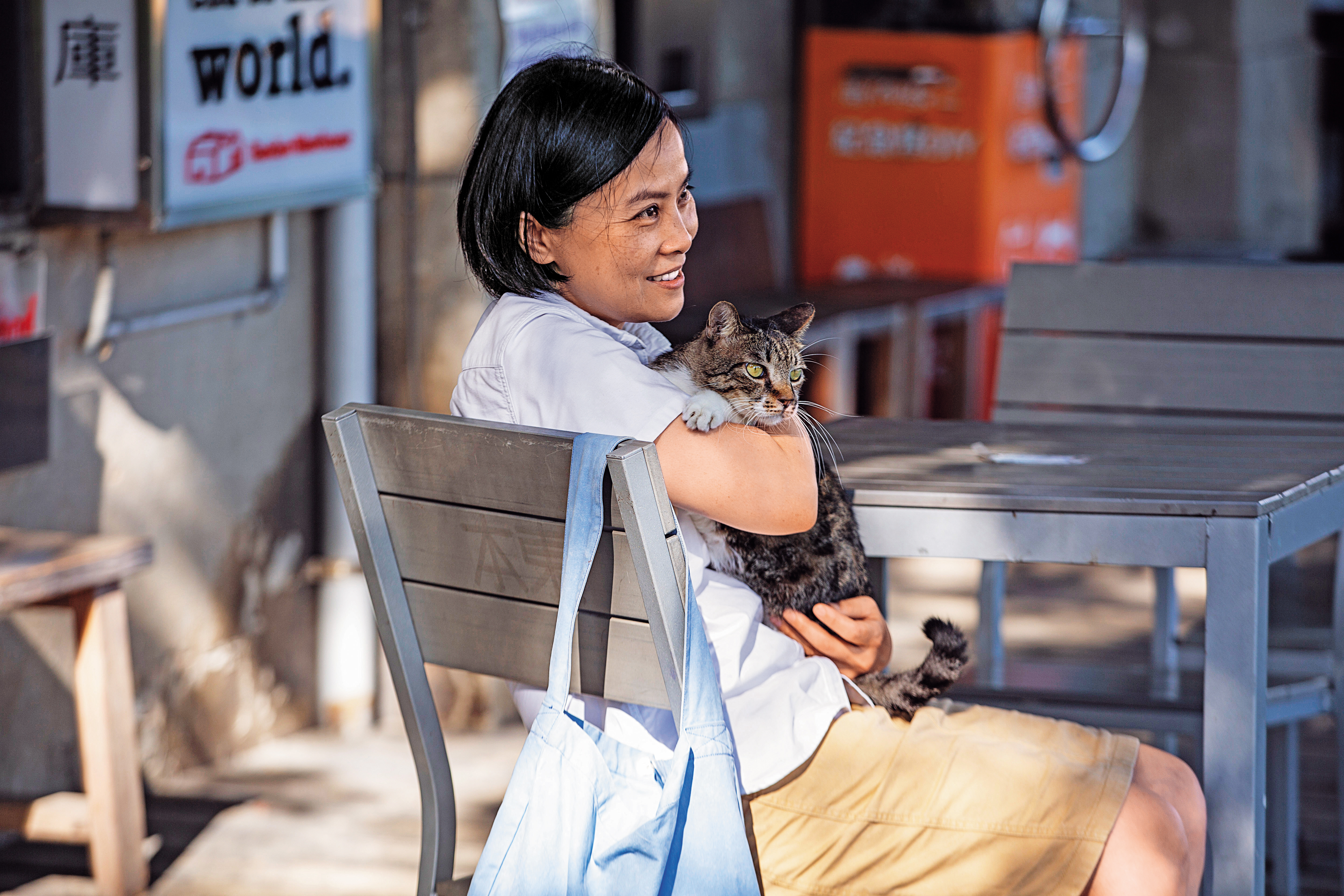 李瑾倫帶我們來到高雄駁二特區的文創商店「本東倉庫商店」，她一走近，駐店的其中一隻魚皮貓「小七」便黏在她身上，十分乖巧。