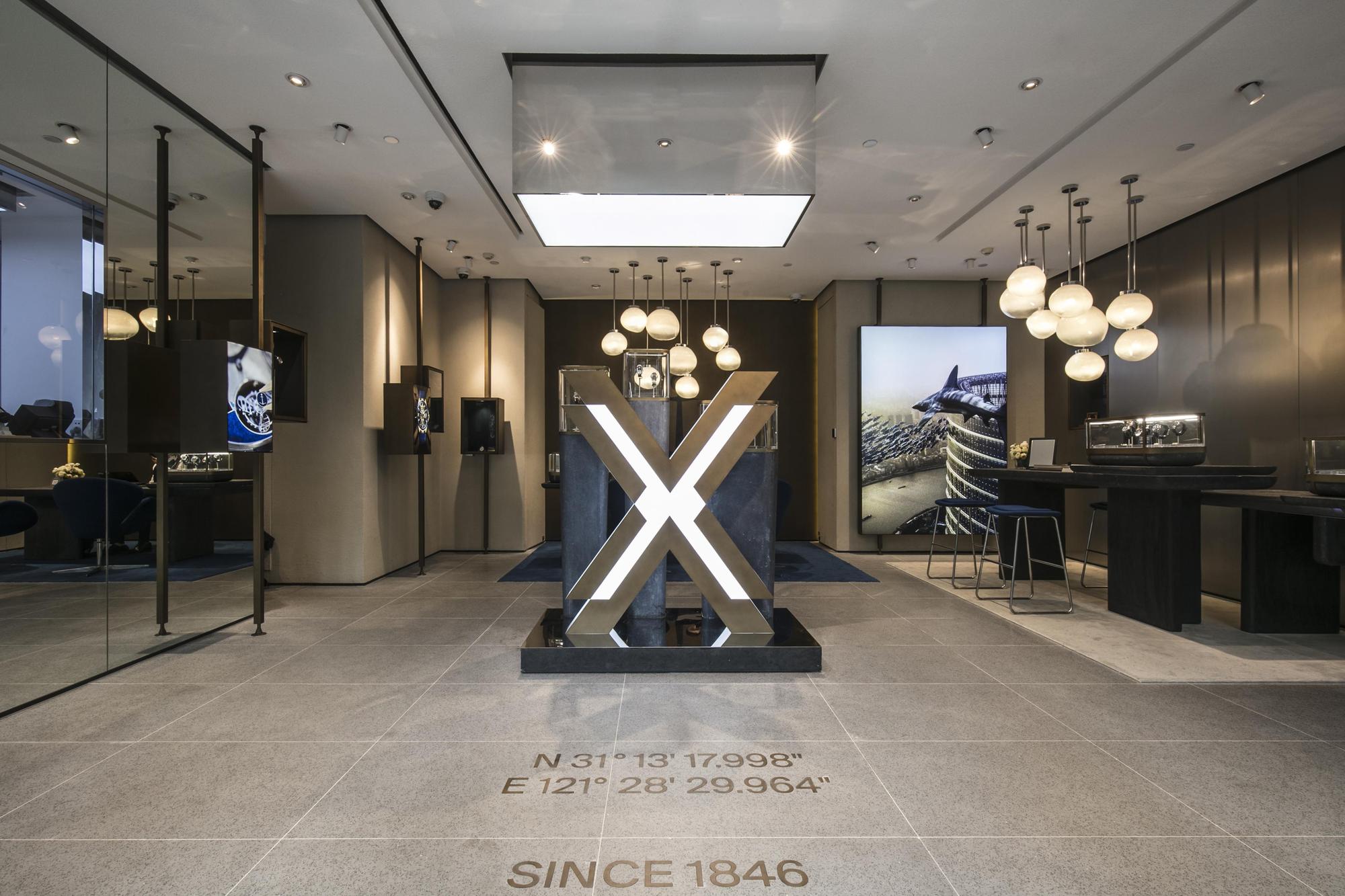 上海專賣店門口大大的X，象徵了雅典創新和探索的挑戰精神。金屬、鏡面和石材的搭配運用，讓內部空間有了延伸感，調性也很沉穩氣派。