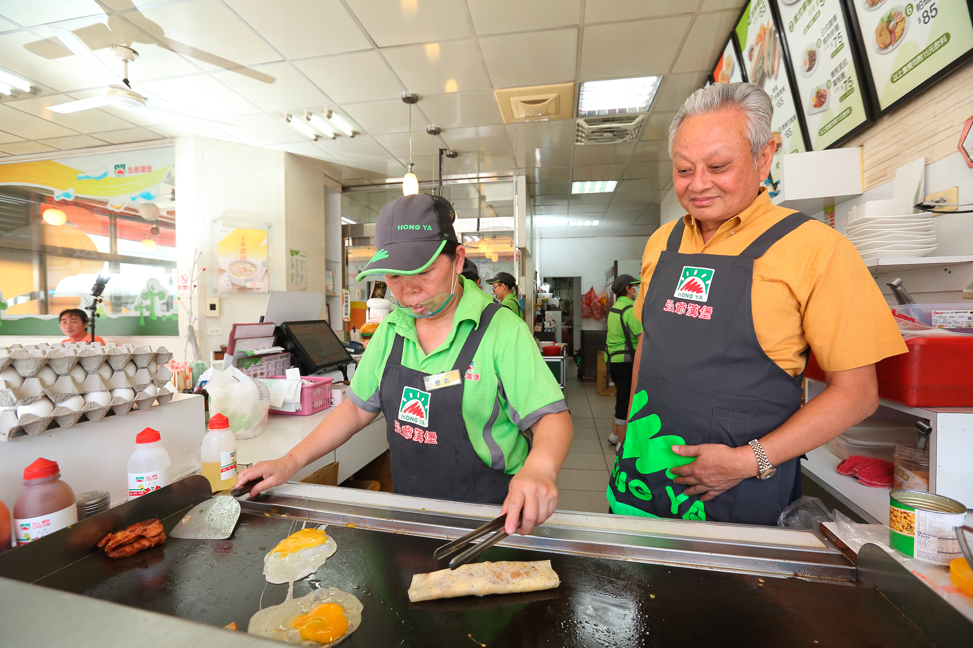 不管三明治或漢堡，許倉賓（右）希望消費者拿到手上時都是口感最佳狀態，因此要求員工煎蛋、煎肉等都有一定順序。