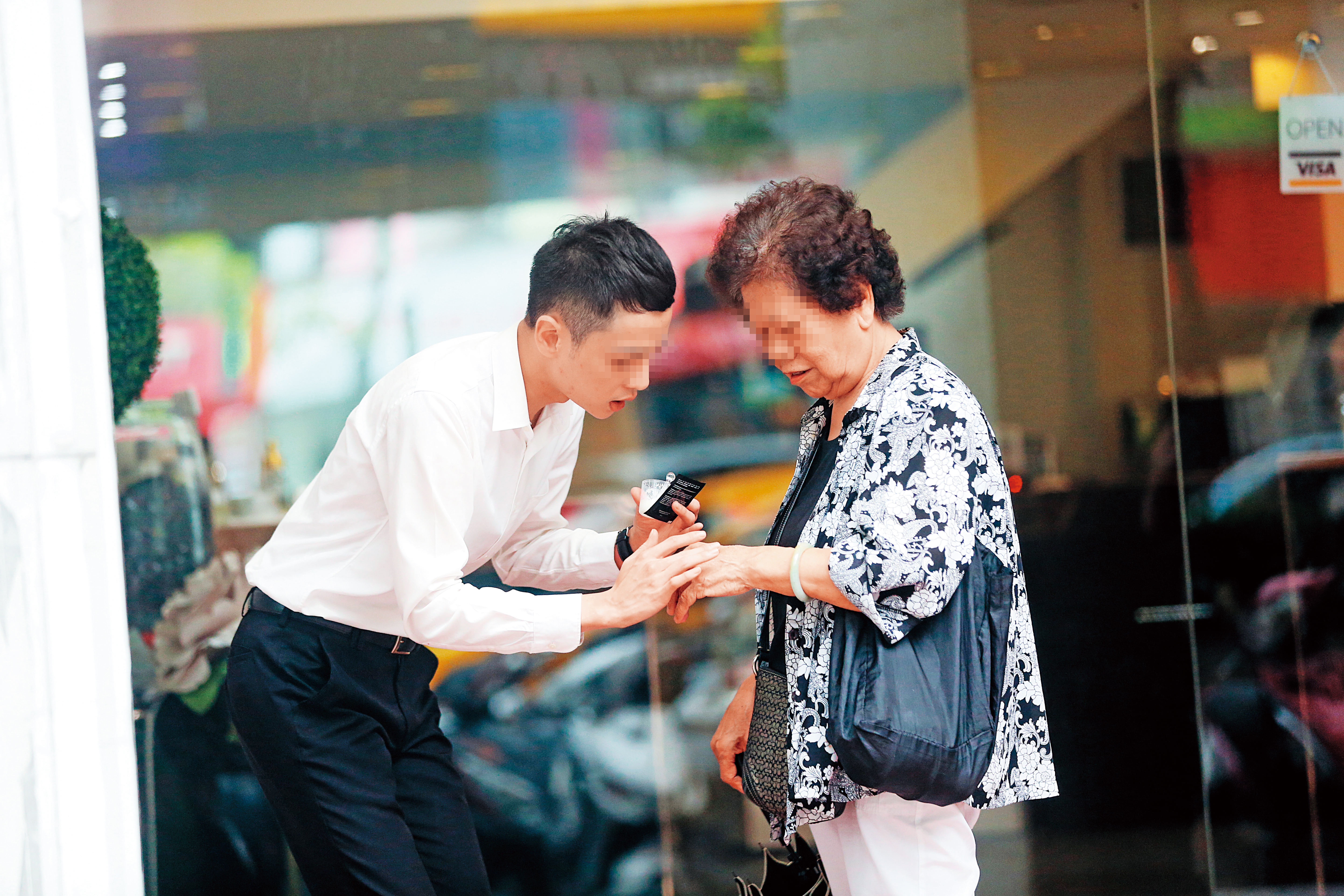 美妝店的男店員在路邊攬客，直接把保養品塗抹在路過的婦人手上。