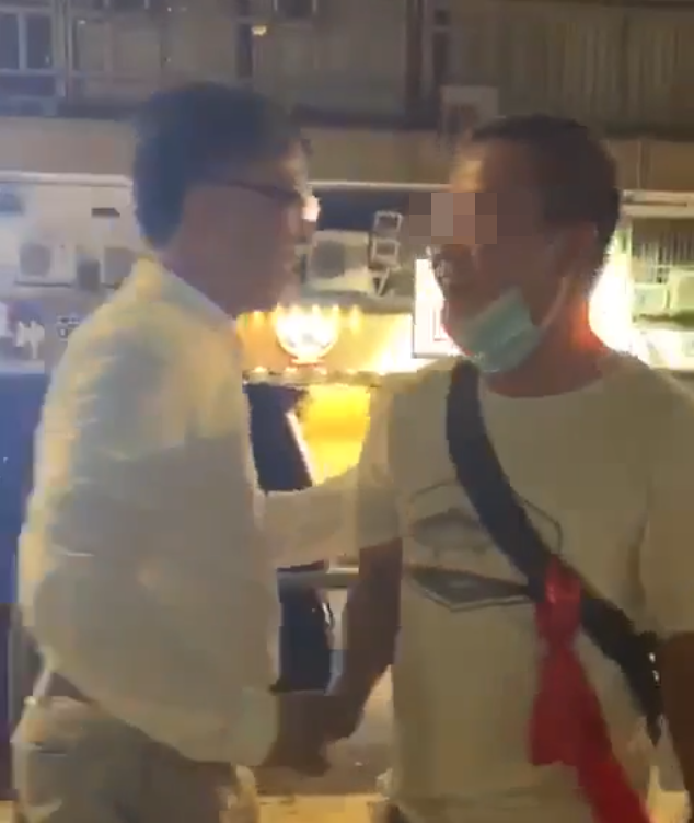議員何君堯與其中一名白衣人握手，還拍肩表示鼓勵。（翻攝自網路影片）