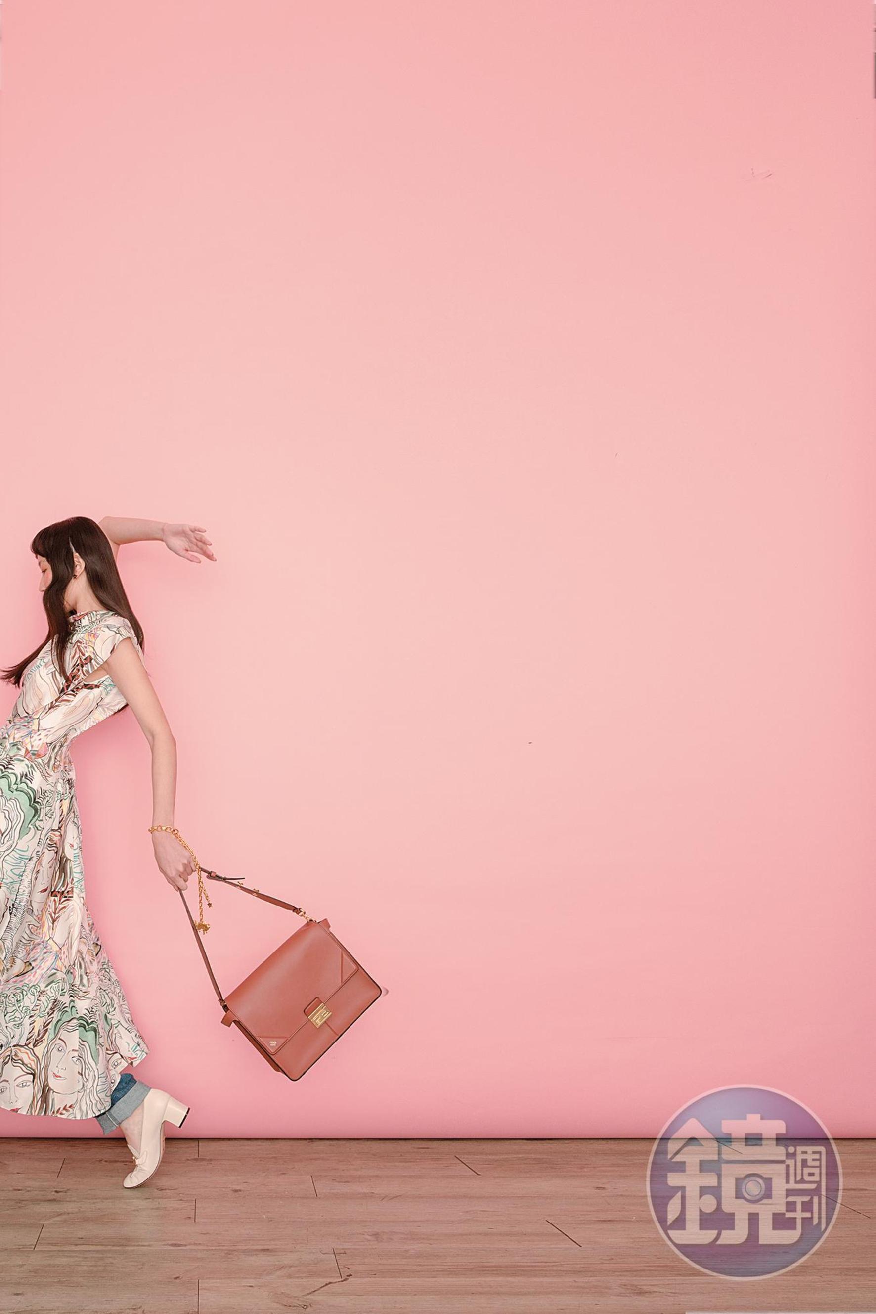 駝色KAN U提包 NT$98,000 by FENDI；不對稱絲質印花洋裝 NT$43,000 by 3.1 PHILLIP LIM；丹寧褲 NT$23,000 by LOEWE；白色馬銜鍊高跟鞋 NT$30,500 by GUCCI；Zodiaddict 灰色雙子座珍珠不對稱耳飾 NT$22,000 by DIOR；Zodiaddict 金色雙子座垂墜項鍊（當手鍊用） NT$62,000 by DIOR。