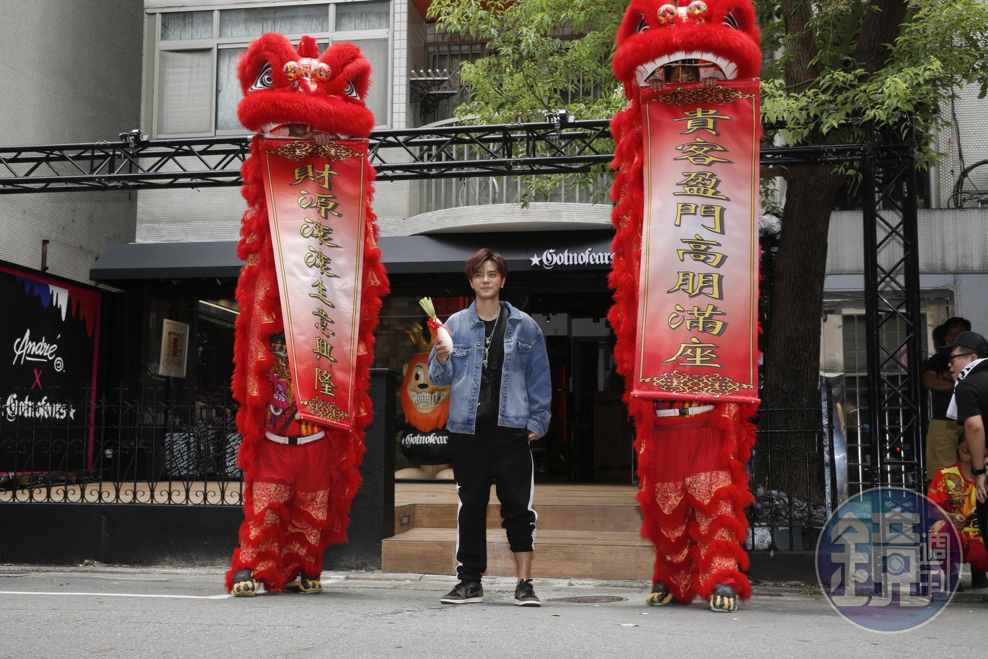 慶祝新店開張,羅志祥手拿象徵「好彩頭」的白蘿蔔,跟舞獅合影。請注意他左腳的褲款,這是故意捲上去的,不是他沒穿好,因為開幕活動他的造型都一直維持這樣沒變過。