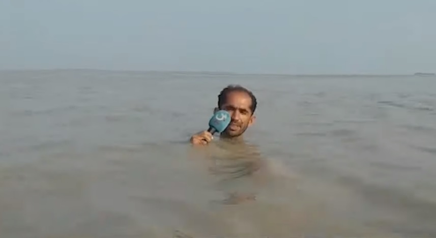 巴基斯坦一名男記者為了報導洪水災情，整個人泡在泥黃色的洪水中，只露出一顆頭和麥克風。（翻攝GTV NEWS）