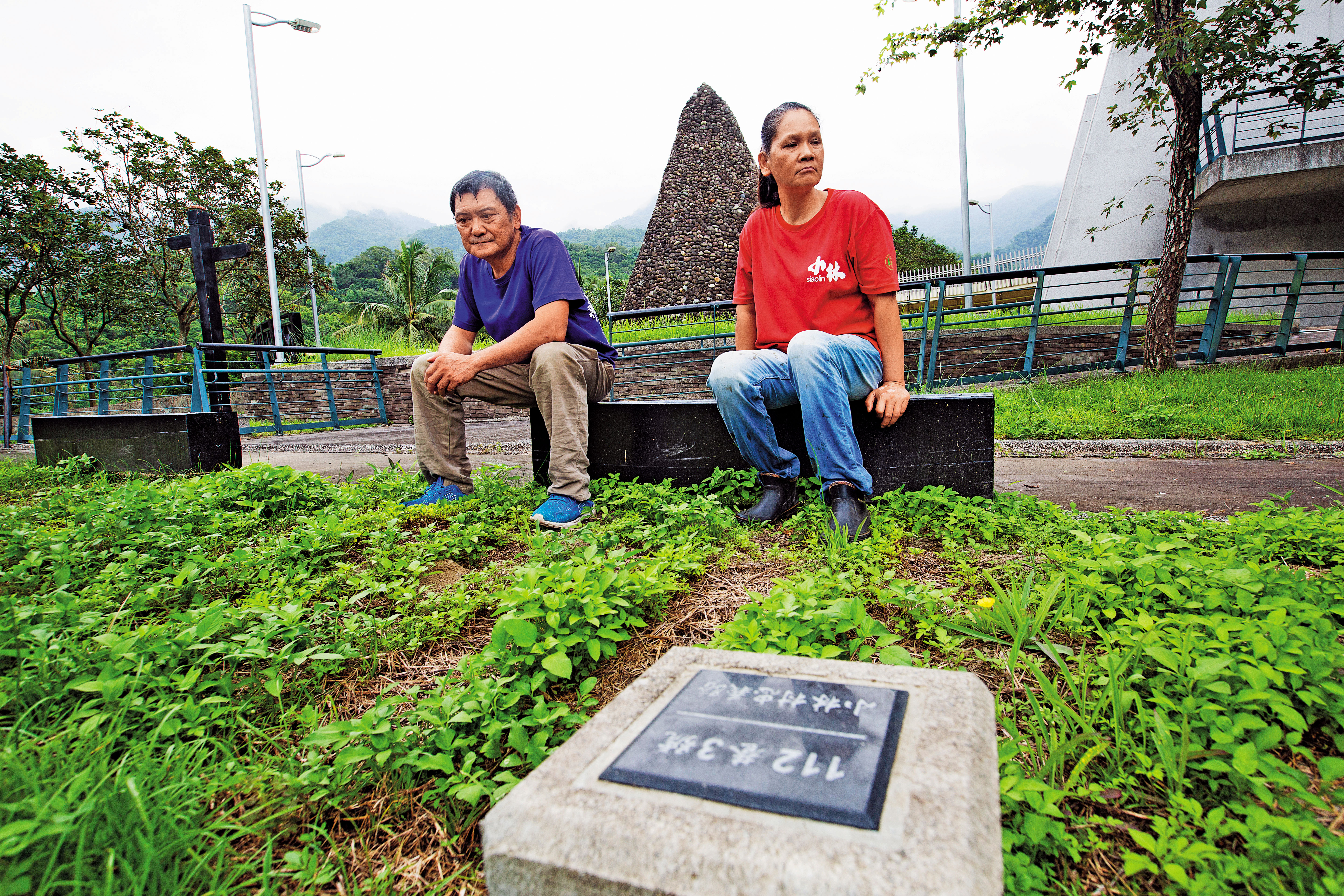 劉秋田(左)坐在紀念公園內,望著老家所在住址忠義路112巷3號,右為太太葉秀霞,也幸運逃出。