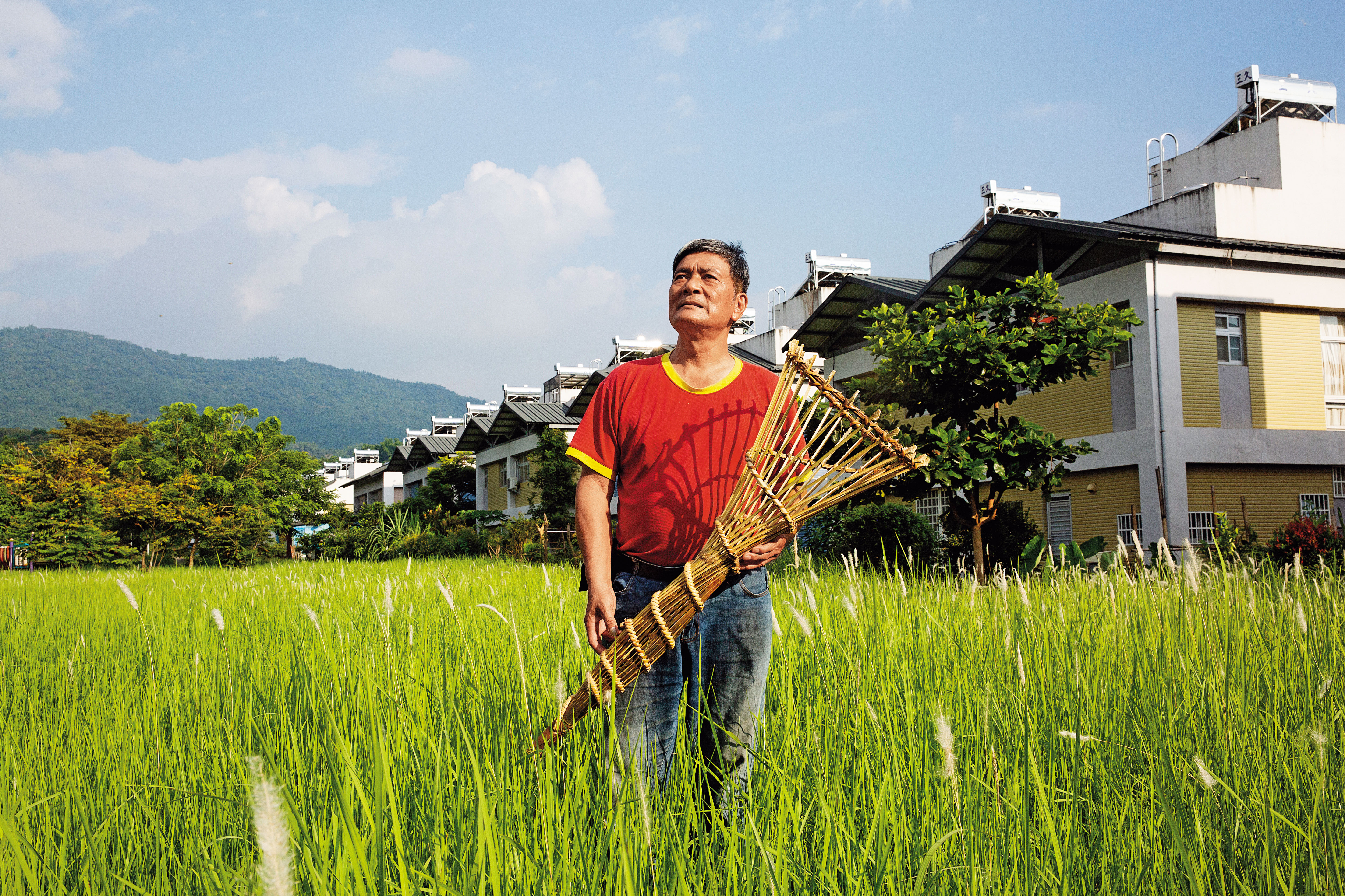 害怕安靜的徐大林，習慣以竹工藝打發時間，同時保留傳統。後方是他現居住的重建區日光小林。
