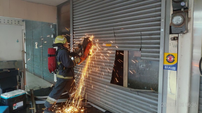 消防隊員鋸開鐵門入內灌救。（翻攝畫面）