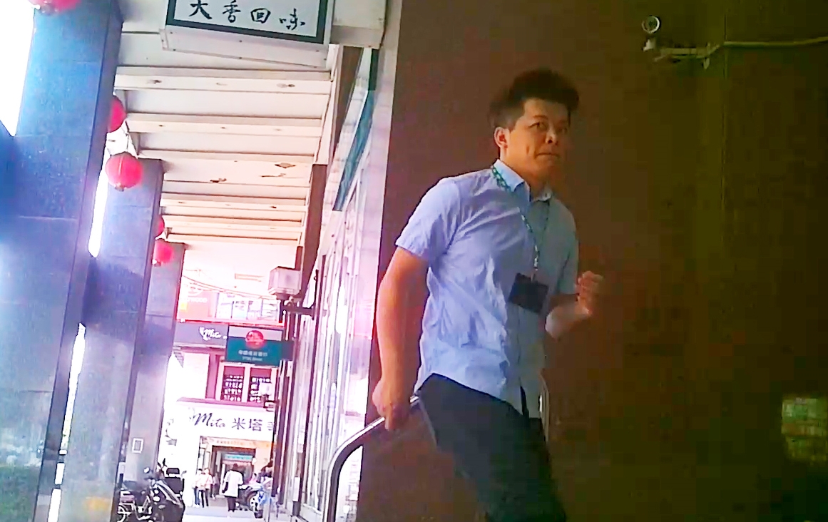 謝維洲似乎誤以為穿著黑衣的本刊記者是討債公司人員,加快腳步進入大樓。